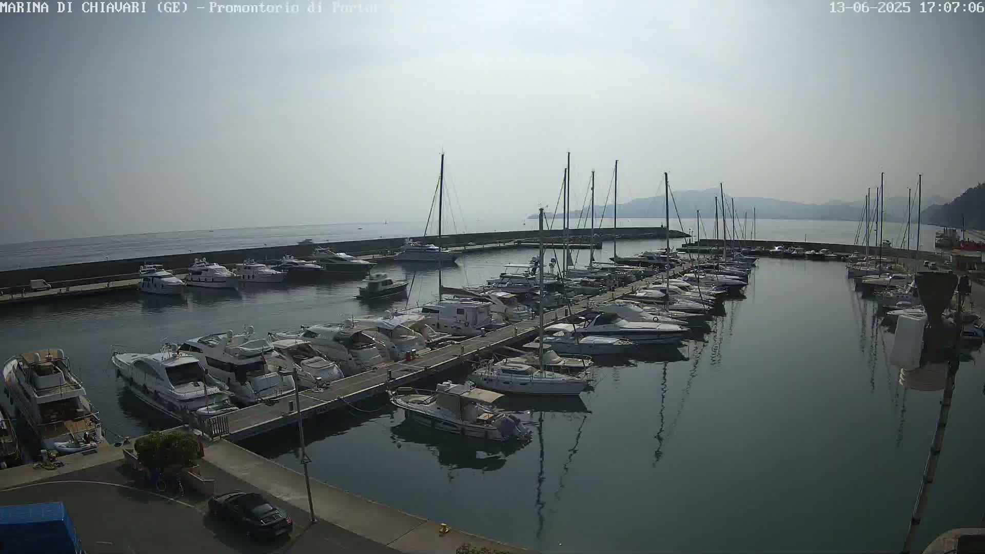 A marina filled with numerous yachts and sailboats on a calm, hazy day.