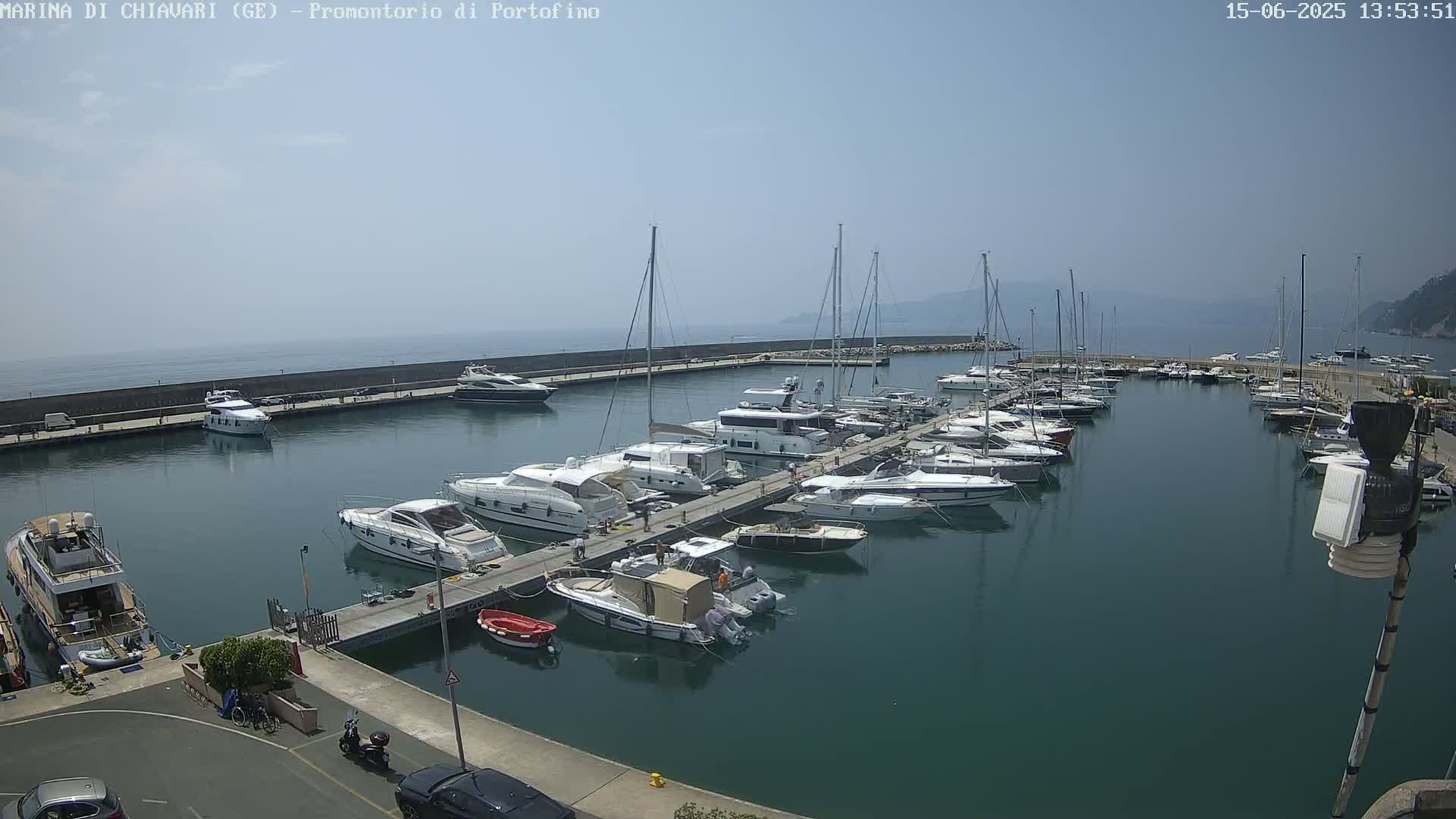 A marina filled with numerous yachts and sailboats is seen on a calm, sunny day.