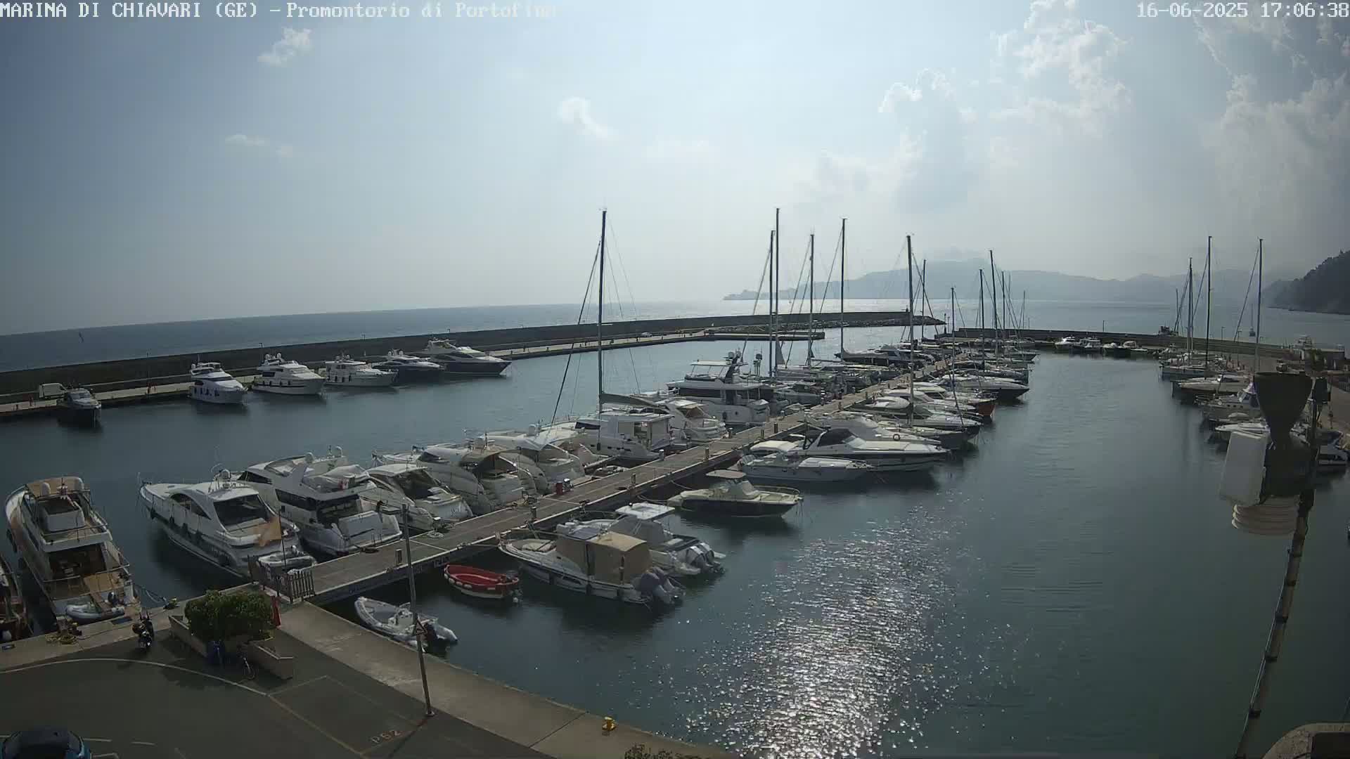 A marina filled with numerous yachts and sailboats is seen on a partly sunny day.