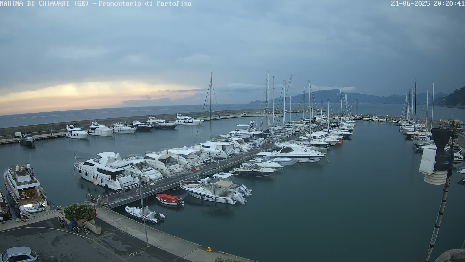 Many yachts and sailboats are docked in a marina under an overcast sky.