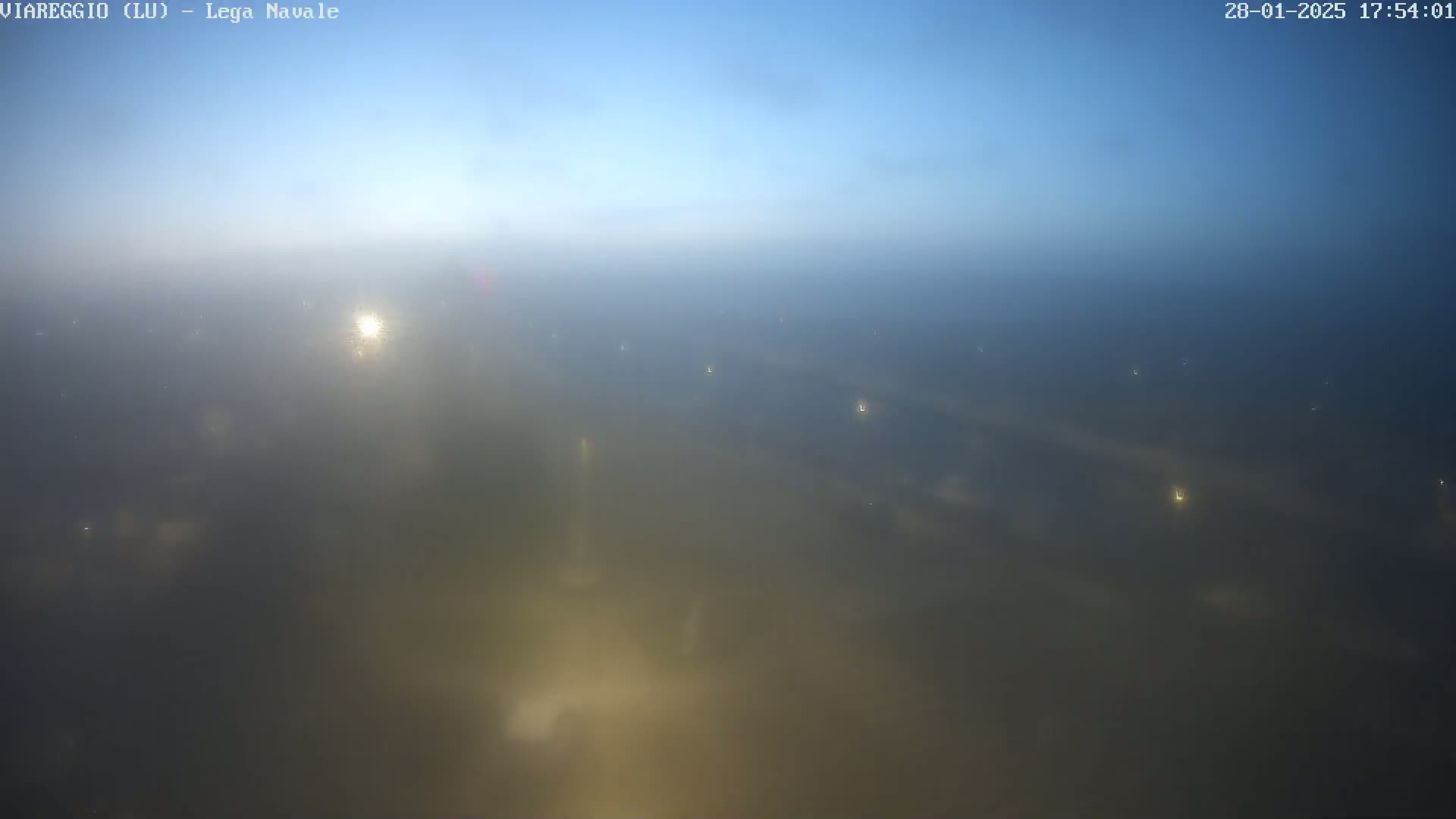 A hazy, foggy landscape is visible at sunset, with a few faint lights scattered across the scene.