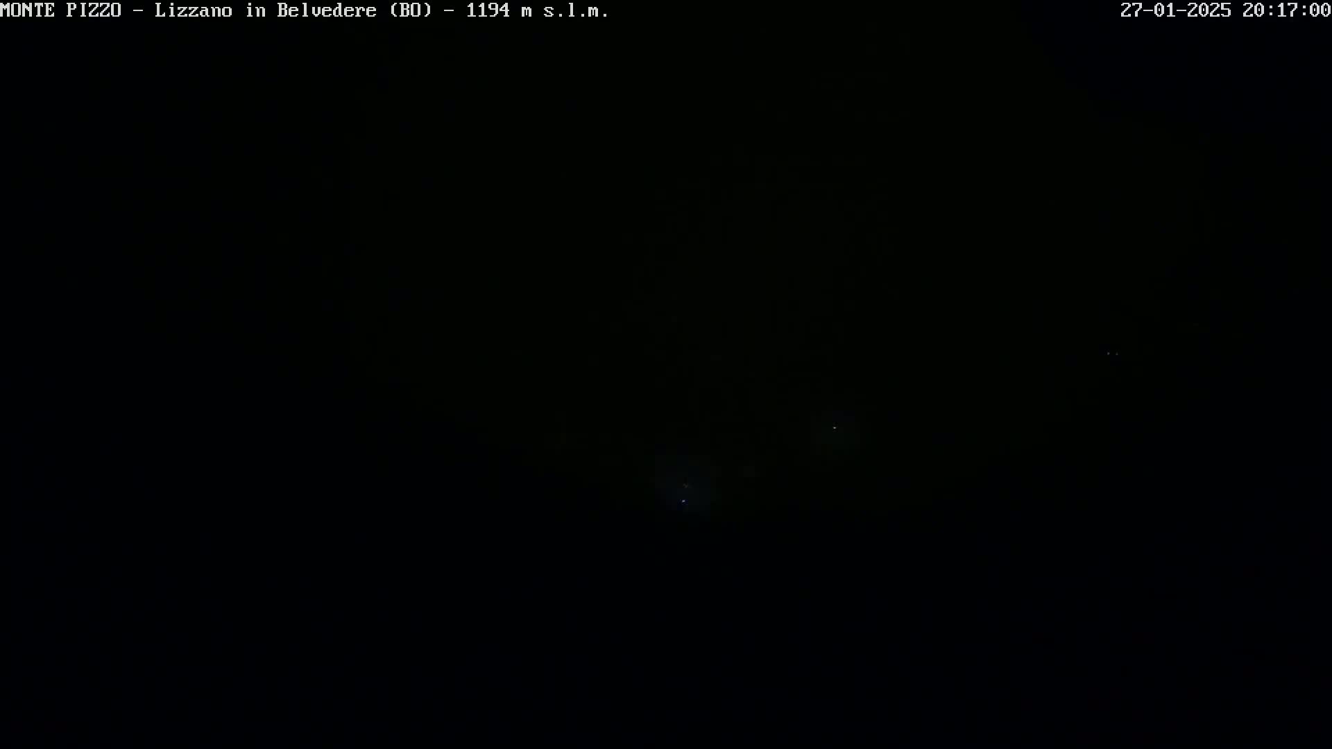 A nighttime outdoor image shows a dark sky with a few faint lights visible in the distance.