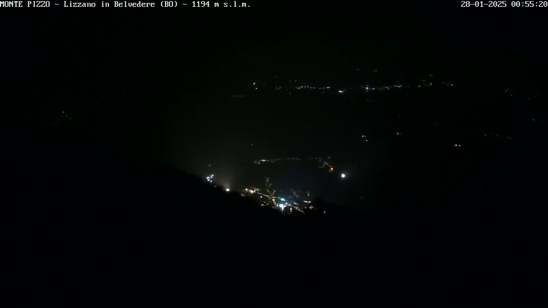 A nighttime, high-angle view shows a valley with sparsely lit settlements below a dark, seemingly clear sky.