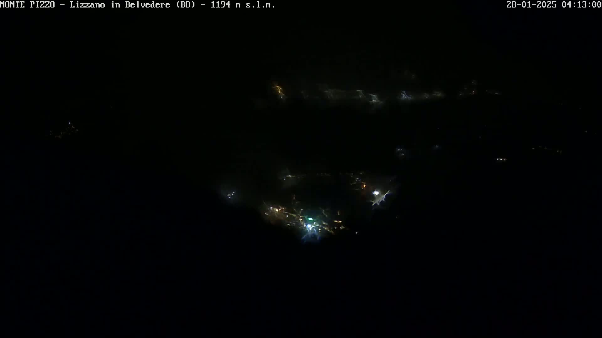 A nighttime, aerial view shows a small cluster of faint lights in the distance.
