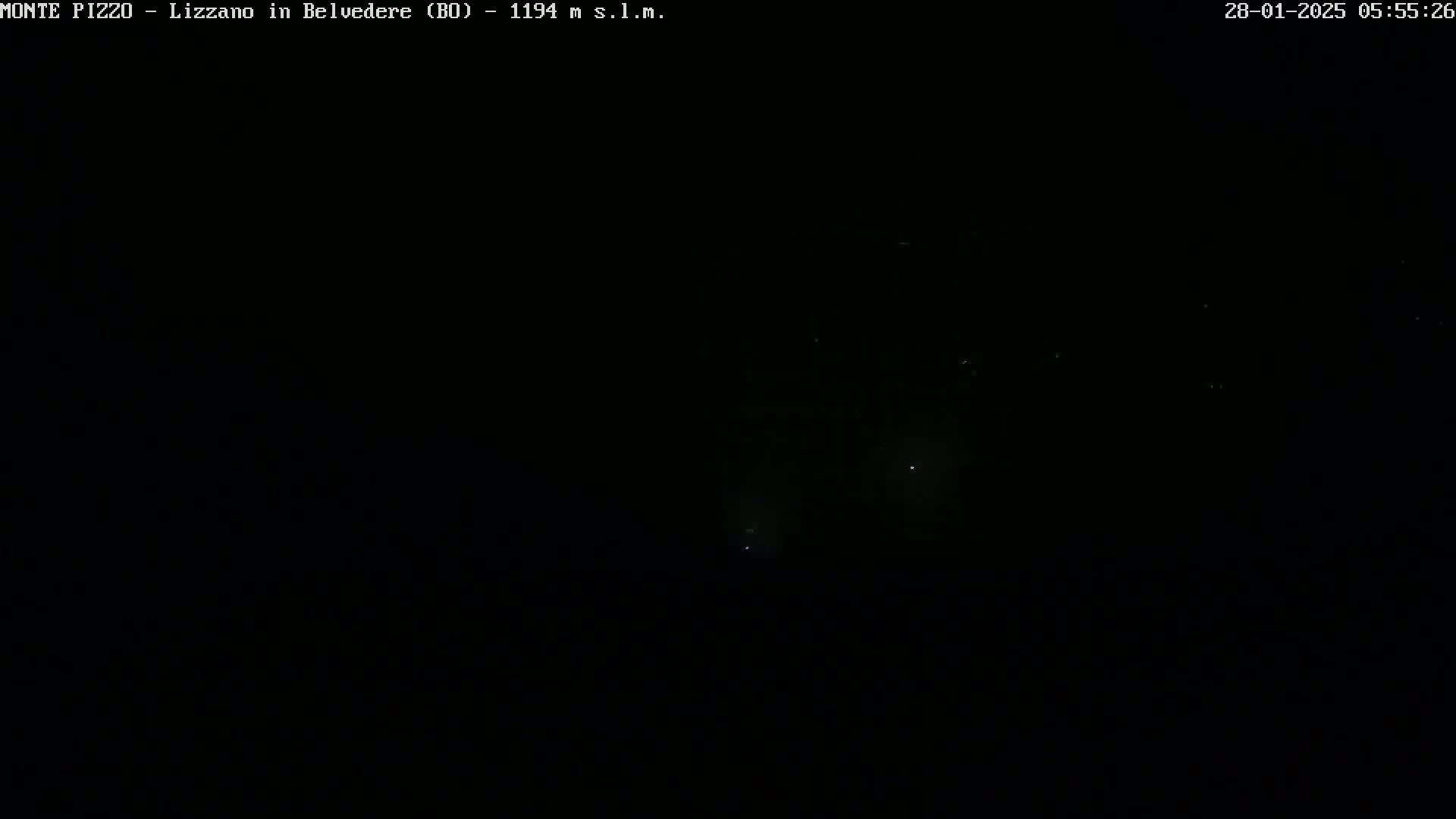 A nighttime, dark sky shows a few faint lights in the distance.