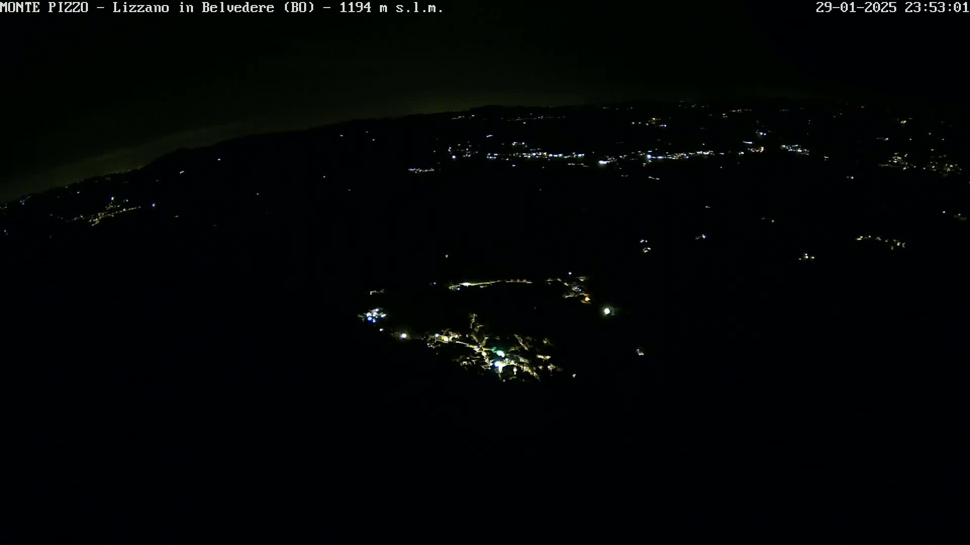 A nighttime, high-angle view of sparsely lit areas in a dark, hilly landscape.