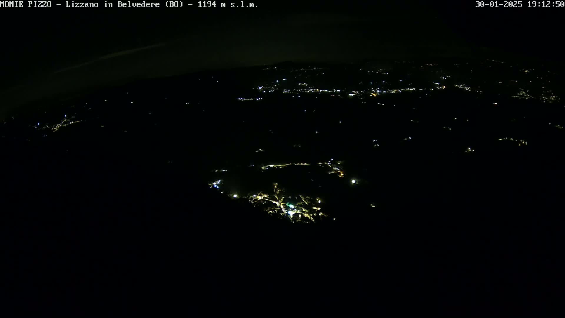 A nighttime, high-angle view shows a dark landscape sparsely dotted with small lights.