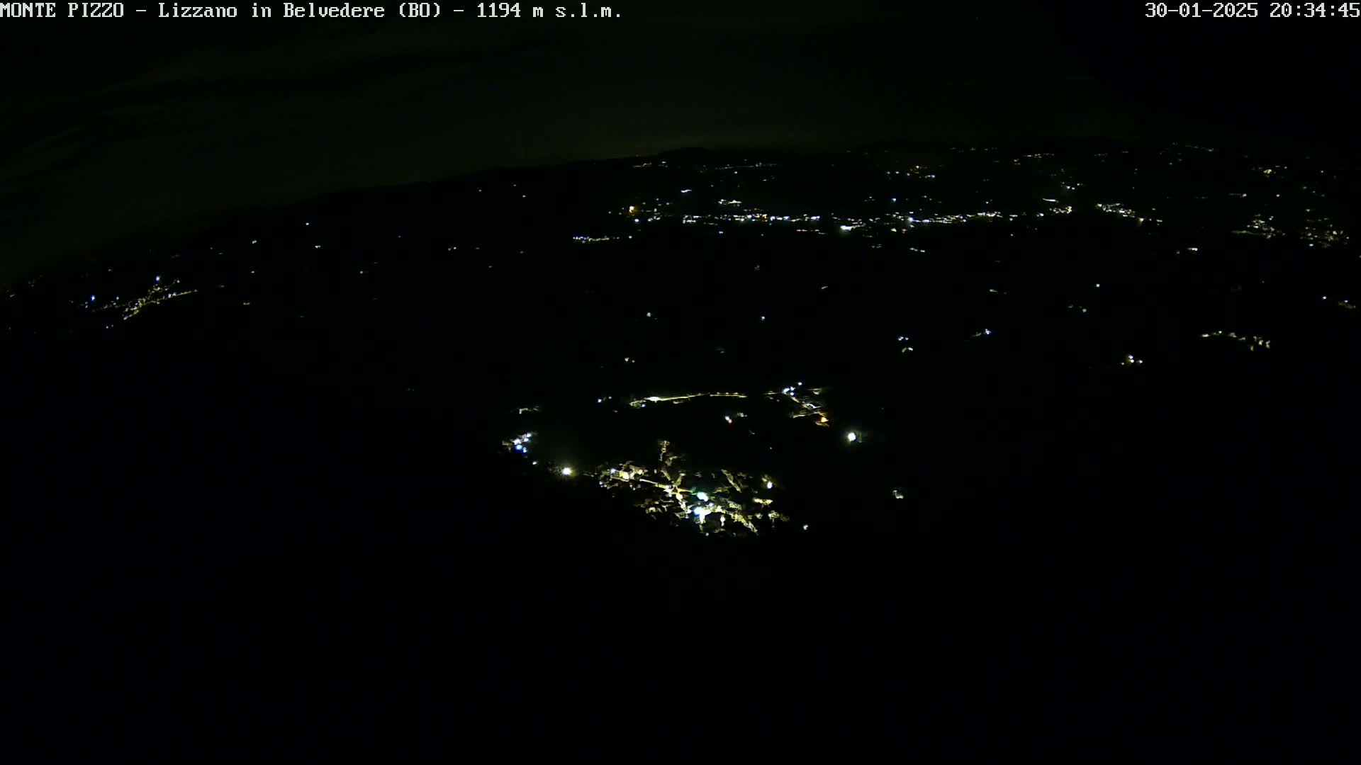 A nighttime aerial view shows a dark landscape speckled with faint, scattered lights.