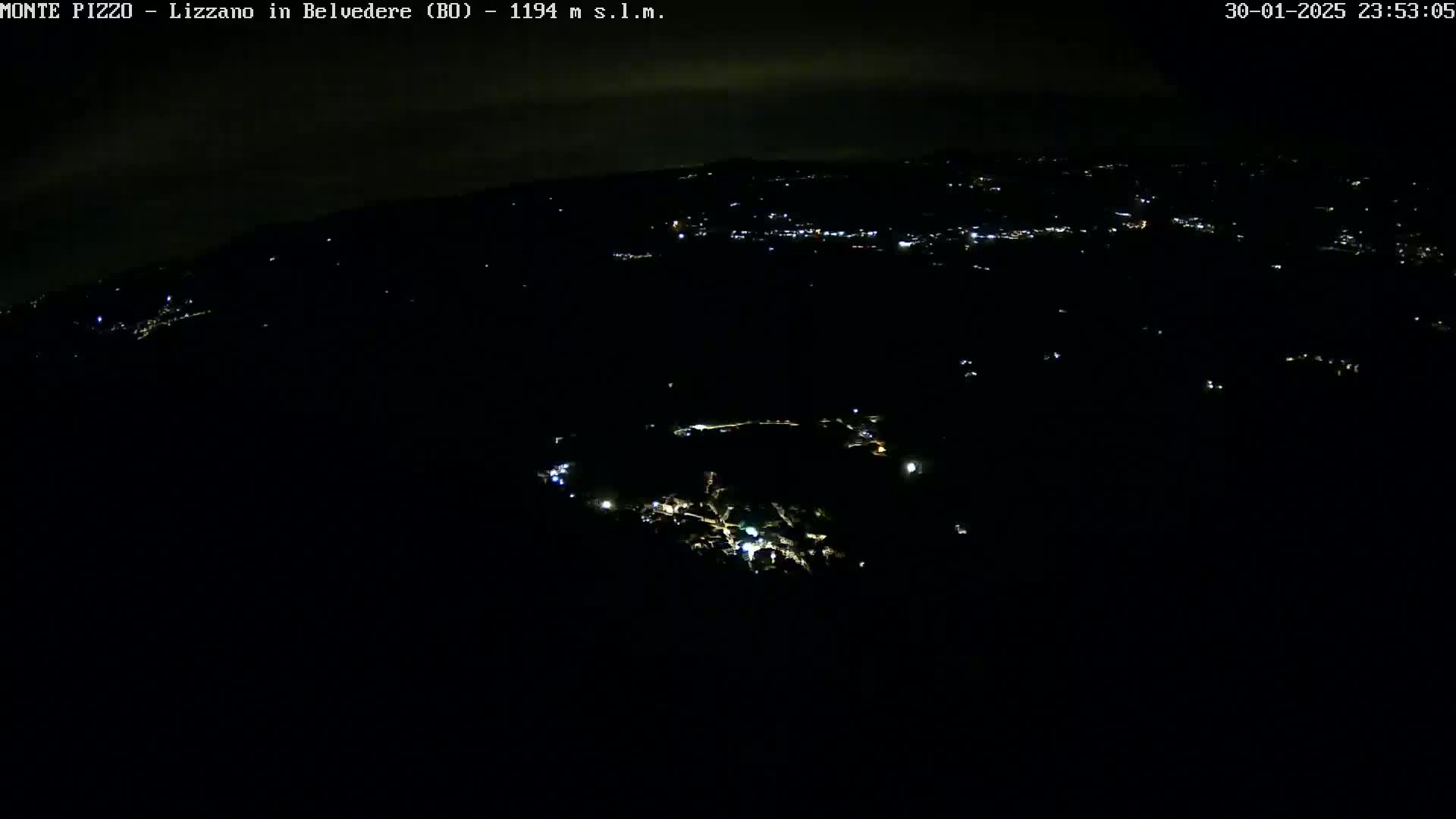 A nighttime aerial view shows a dark landscape speckled with small, scattered lights, under a mostly clear sky.
