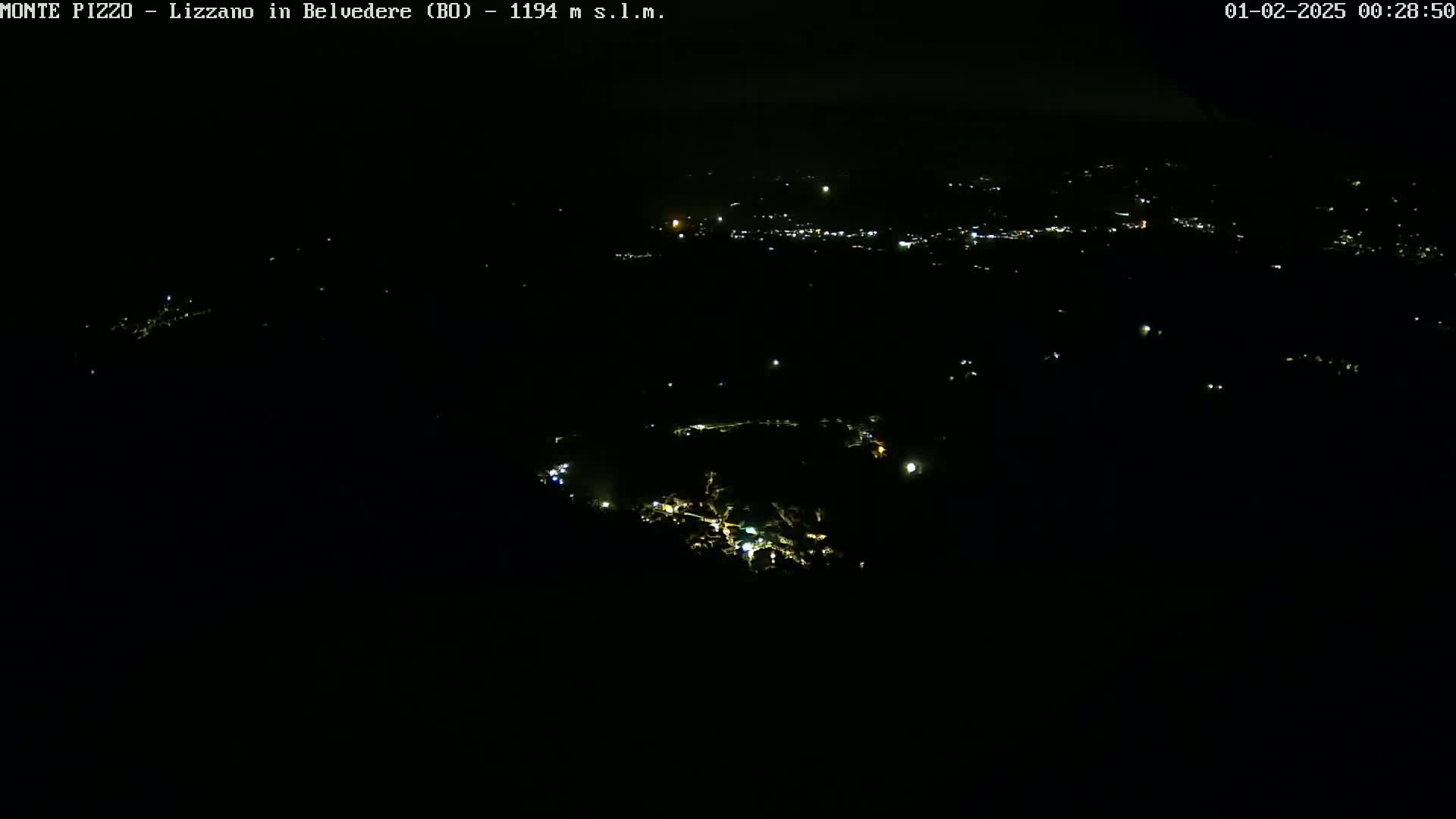 A nighttime, high-angle view shows a scattering of small lights across a dark landscape.
