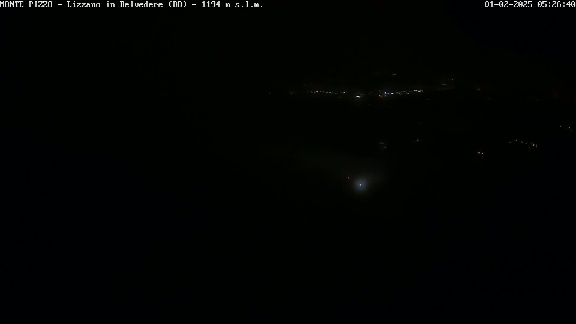A dark, nighttime landscape is visible, showing a few faint lights in the distance.
