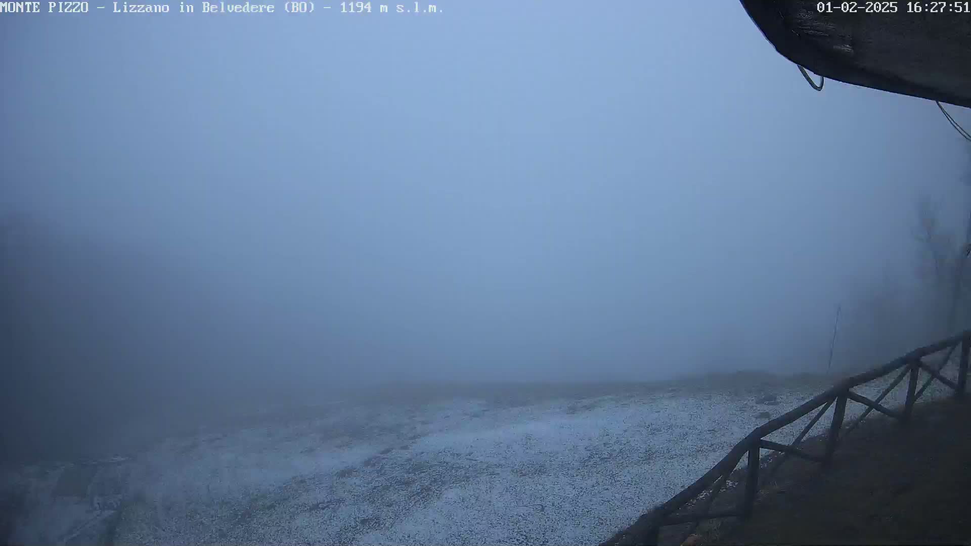 A snow-dusted landscape is visible through a dense fog.