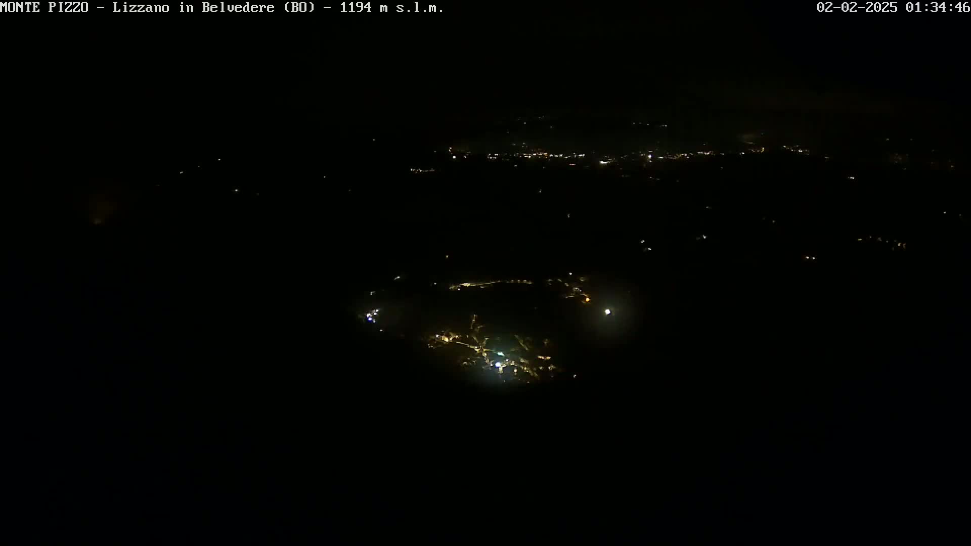 A nighttime, high-angle view shows a small town with scattered lights against a dark sky.
