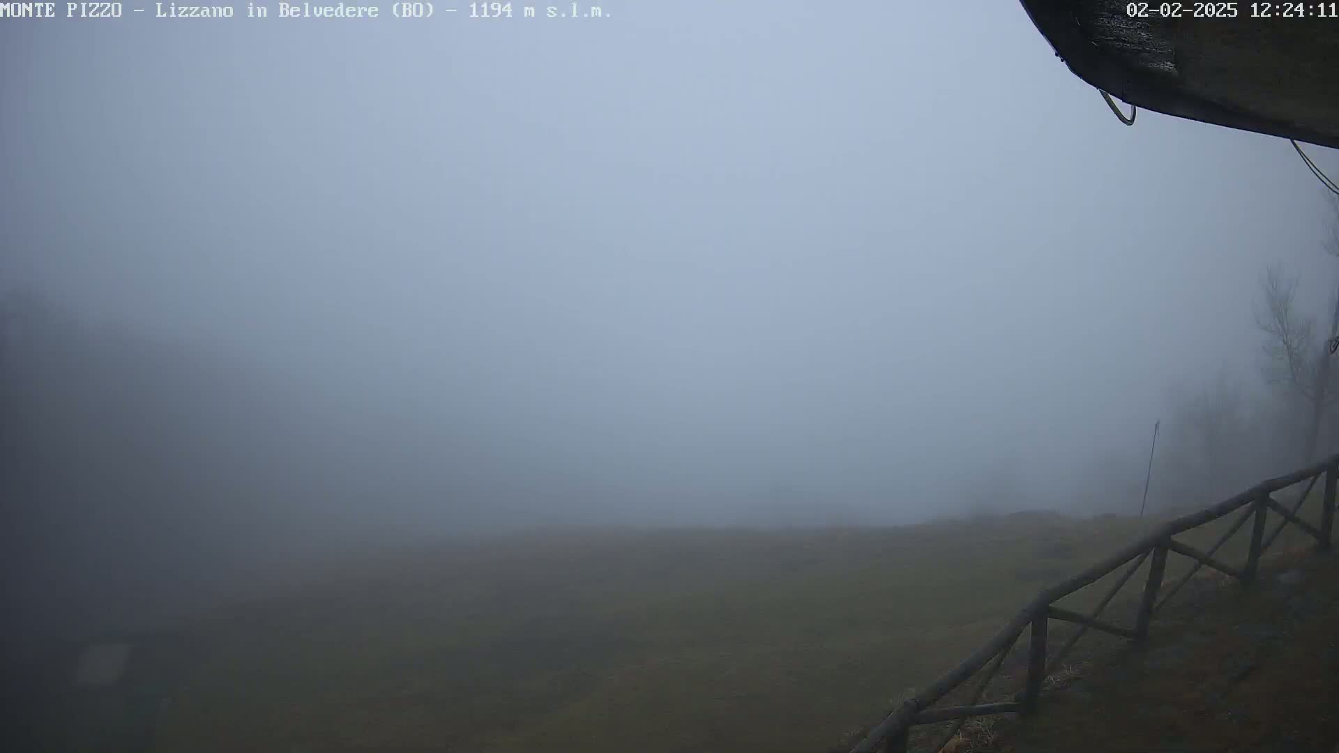 A foggy landscape is visible, featuring a wooden fence in the foreground and a flat expanse of land stretching to the horizon.