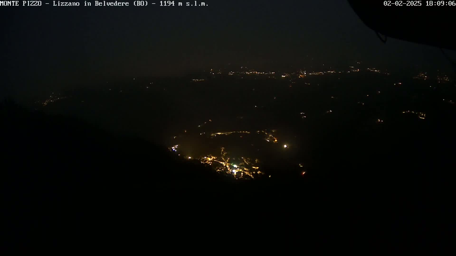 A nighttime, high-angle view shows a cluster of small, scattered lights in a dark, expansive landscape.