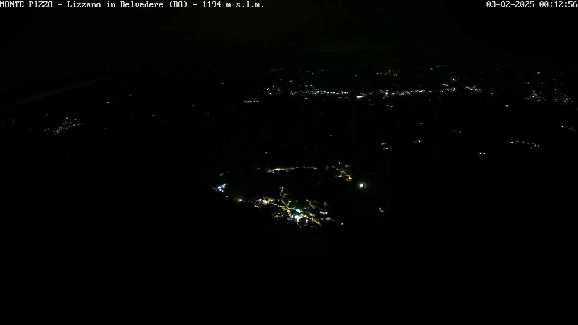 A nighttime aerial view shows a small town with scattered lights in a dark, seemingly clear sky.