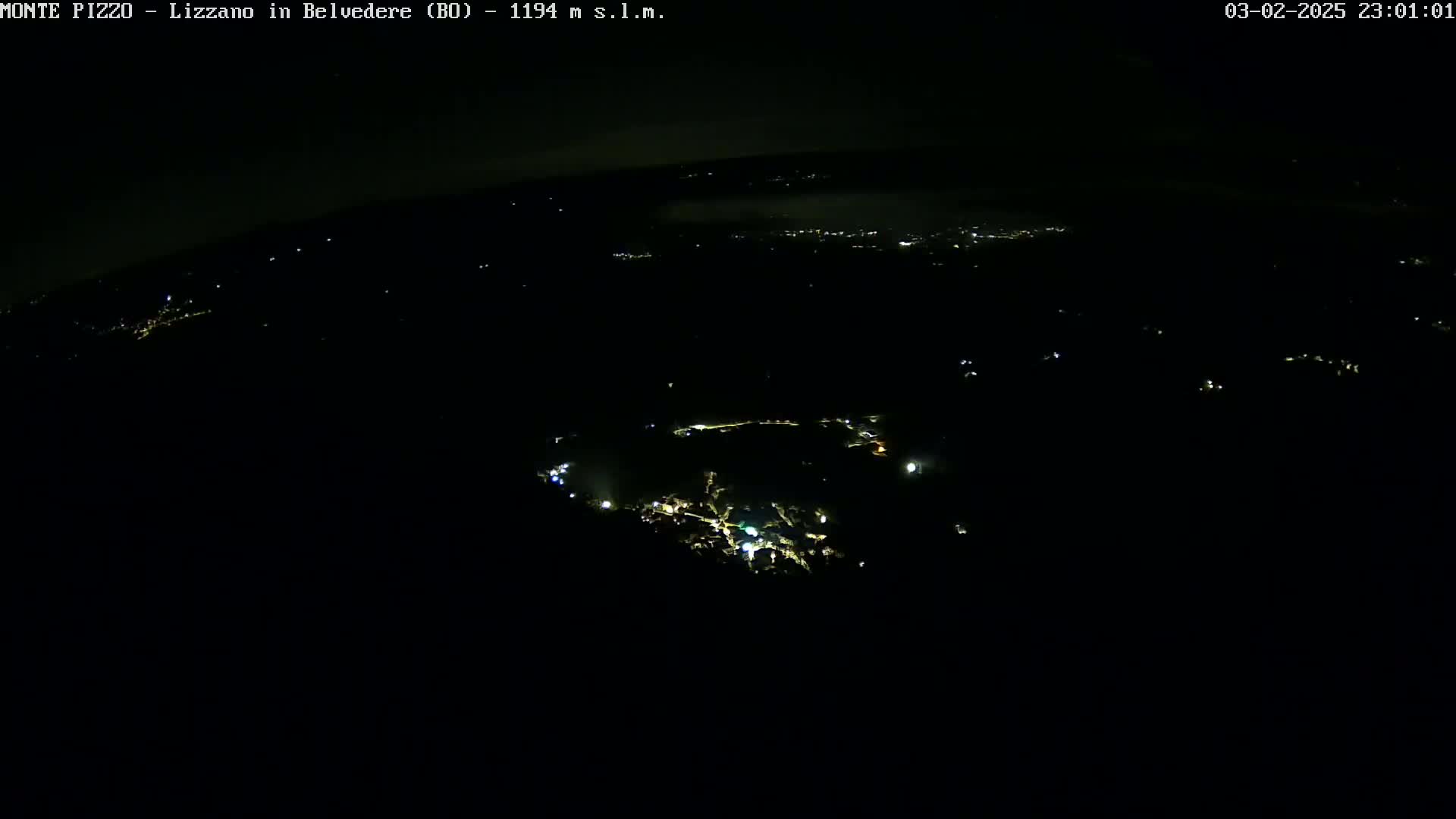 A nighttime aerial view shows a small town with scattered lights under a dark, clear sky.