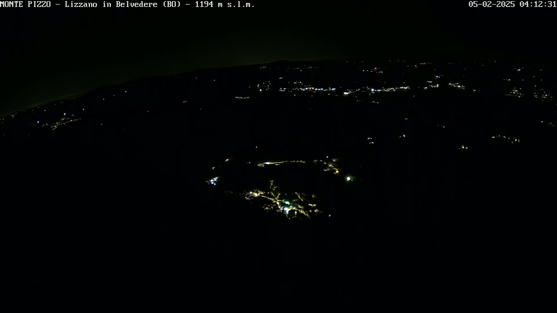 A nighttime, high-angle view shows a dark landscape with sparsely scattered lights illuminating a small town or village.