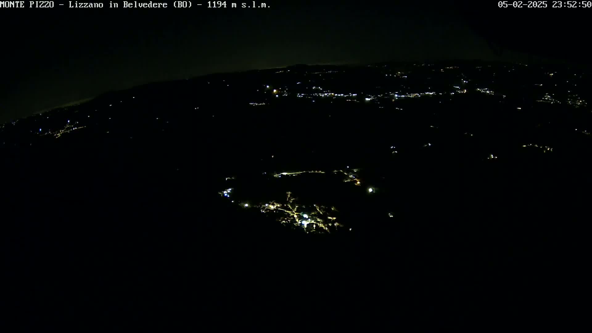 A nighttime, high-angle view shows a dark landscape sparsely dotted with small, scattered lights.