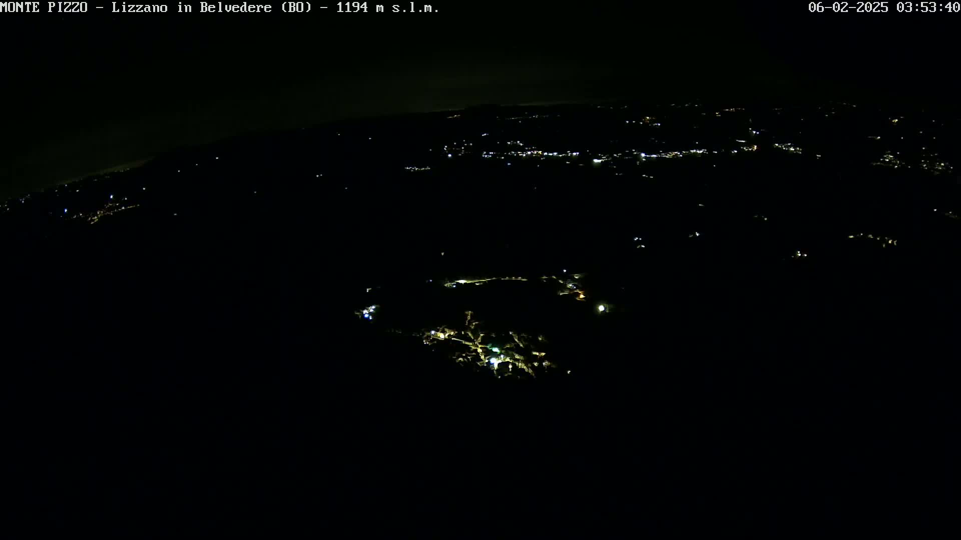 A nighttime aerial view shows a dark landscape with sparsely scattered lights below.