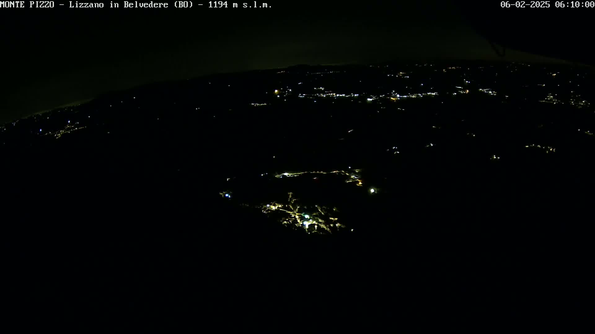 A nighttime, high-angle view shows a dark landscape sparsely dotted with small, scattered lights.