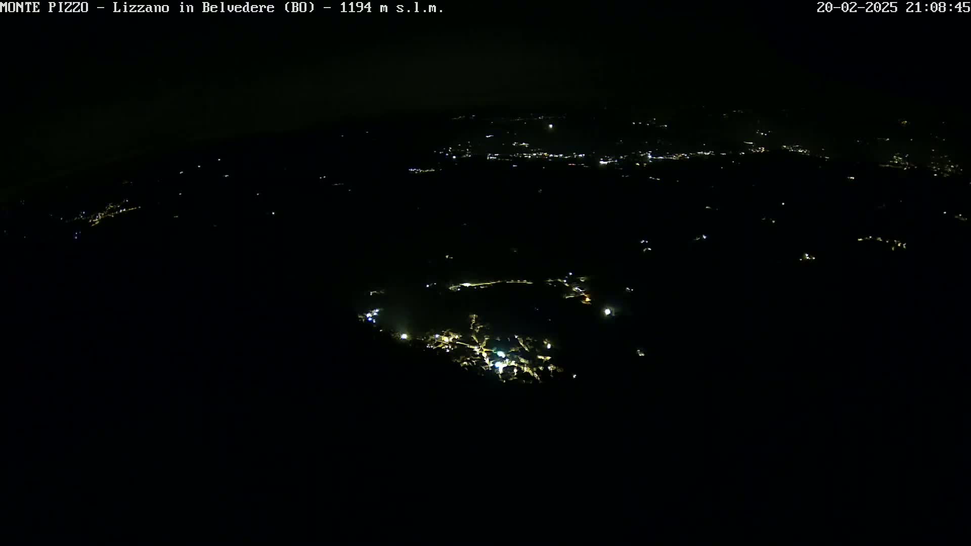 A nighttime, high-angle view shows a small town illuminated by scattered lights against a completely dark background.