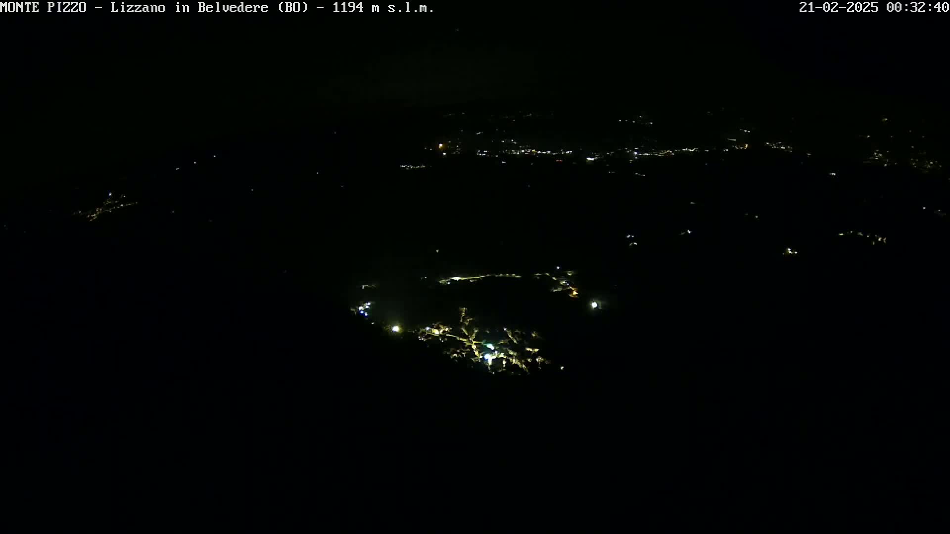 A nighttime aerial view shows a sparsely lit landscape with a small town visible in the distance.