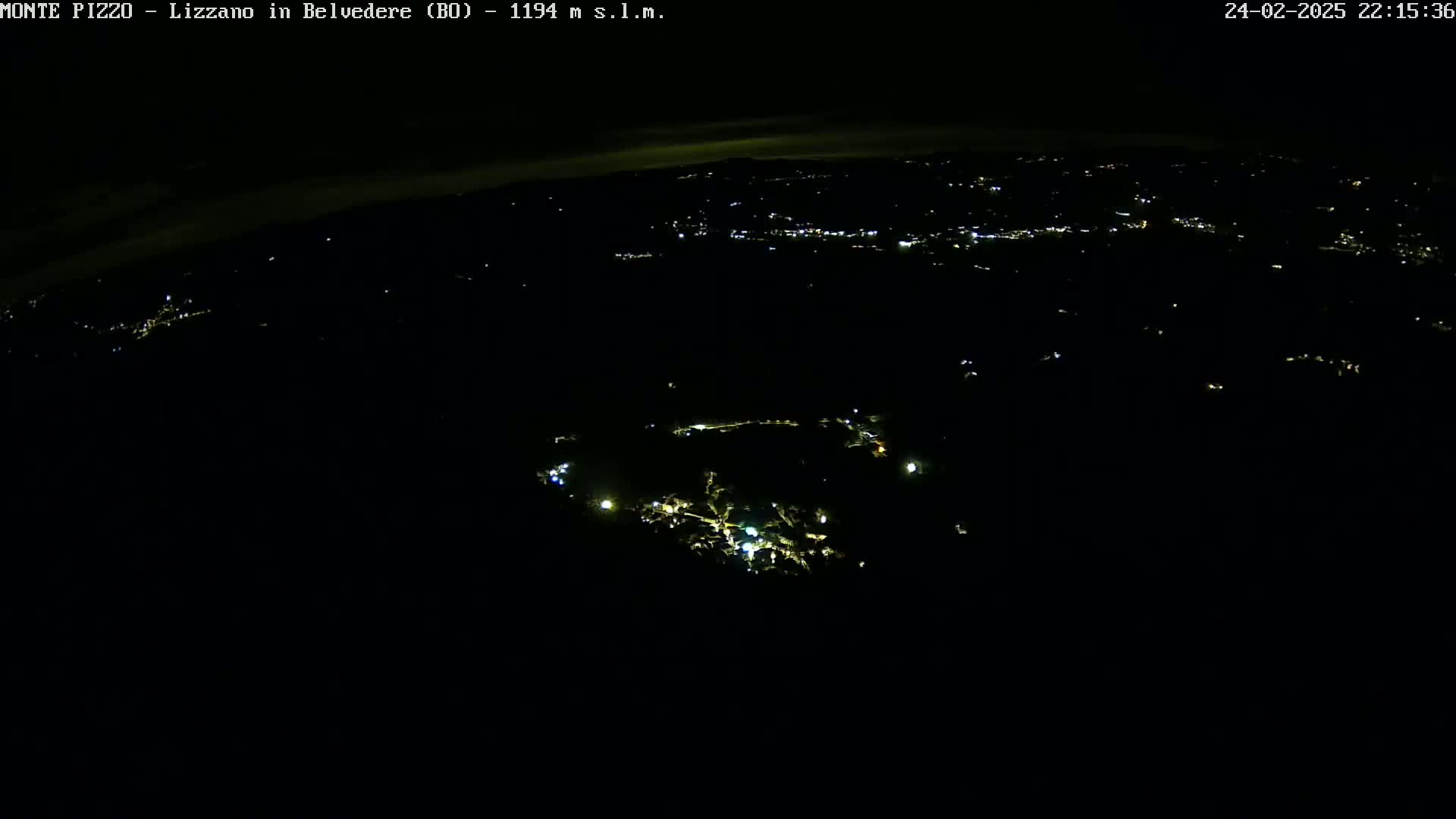 A nighttime, high-angle view shows a dark landscape sparsely dotted with small, scattered lights.