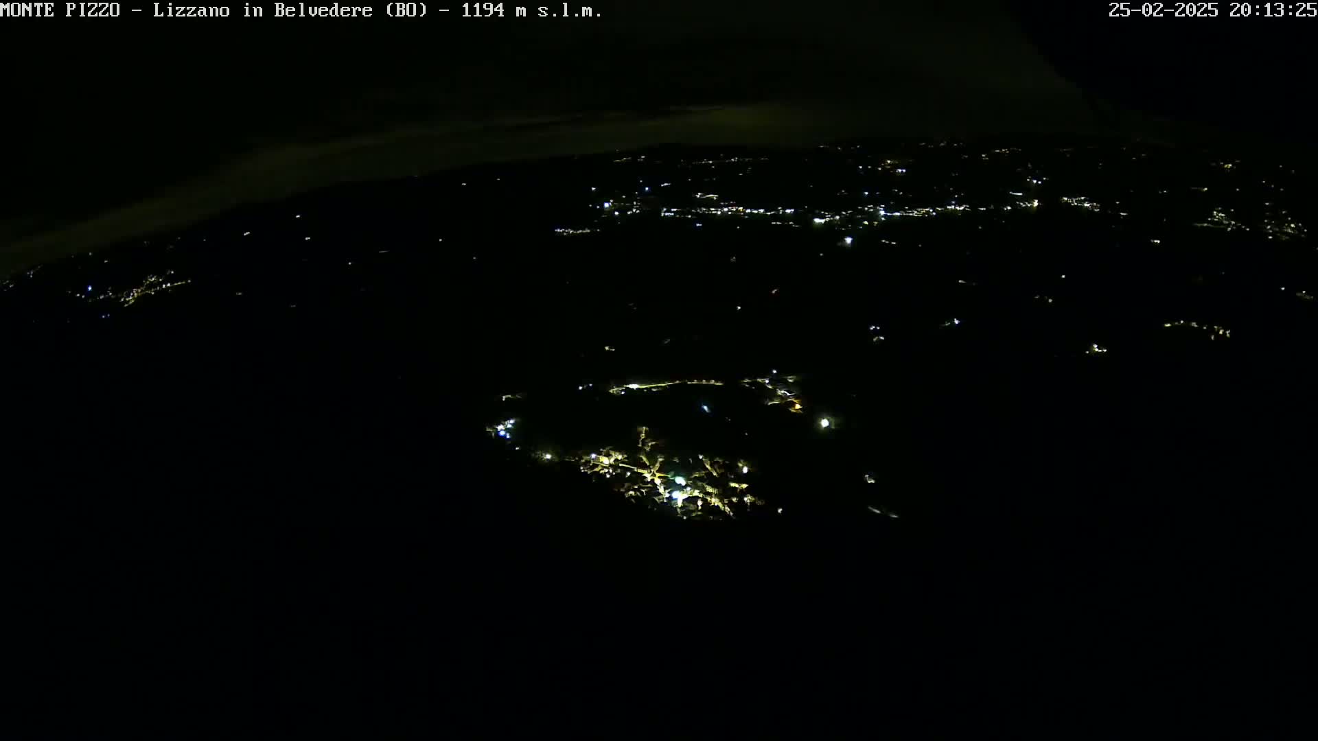 A nighttime, aerial view shows a sparsely lit landscape with clusters of lights suggesting towns or villages in the distance.