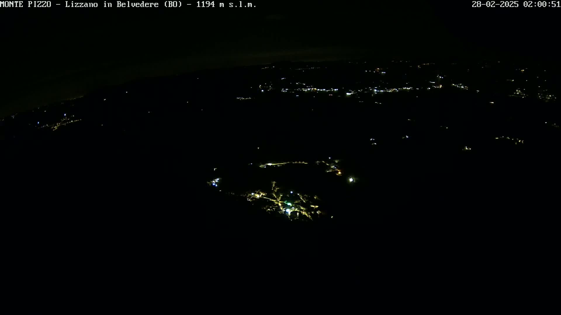 A nighttime aerial view shows a dark landscape with sparsely scattered lights illuminating a small town or village.