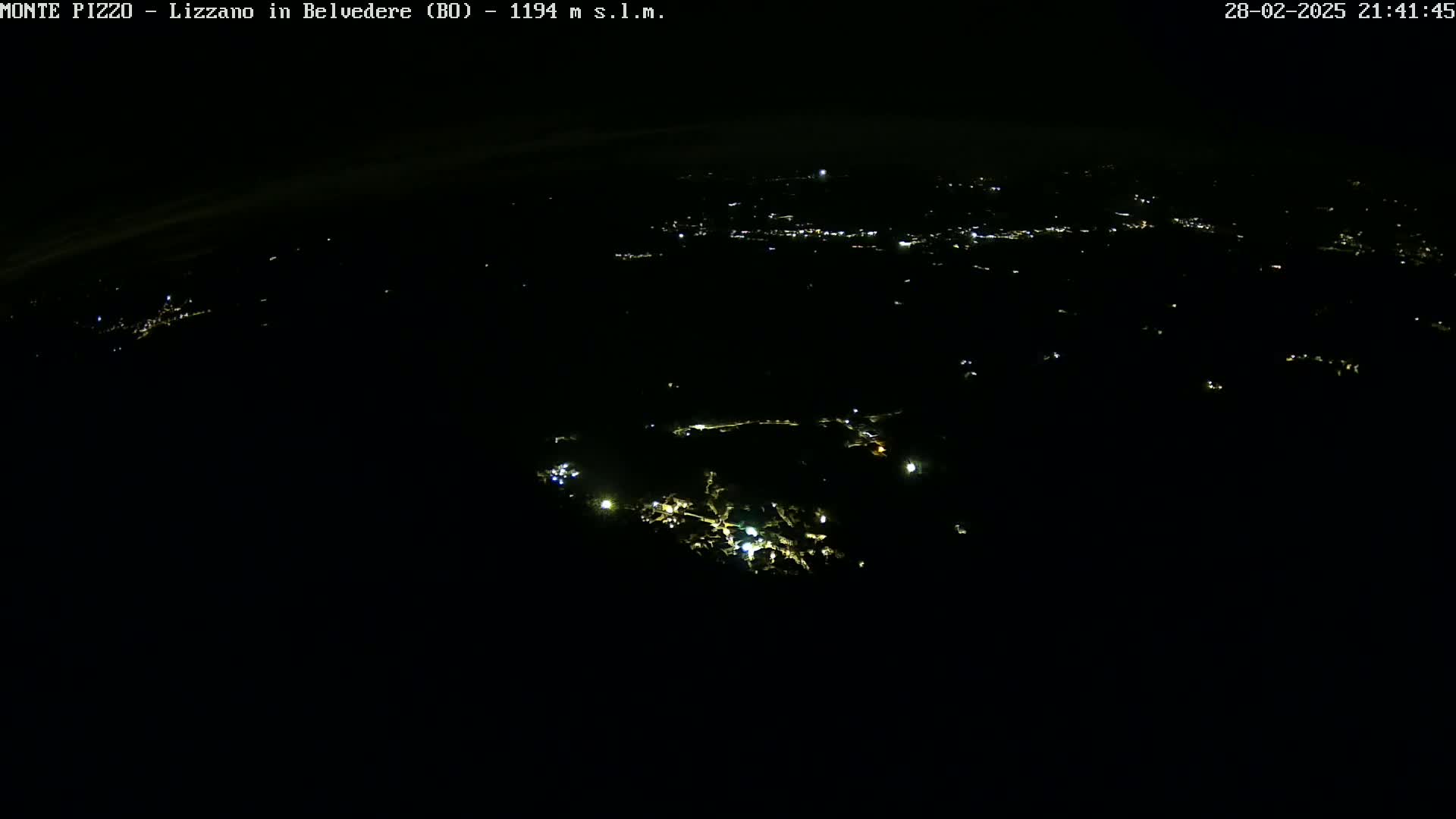 A nighttime, aerial view shows a dark landscape sparsely dotted with small, scattered lights.