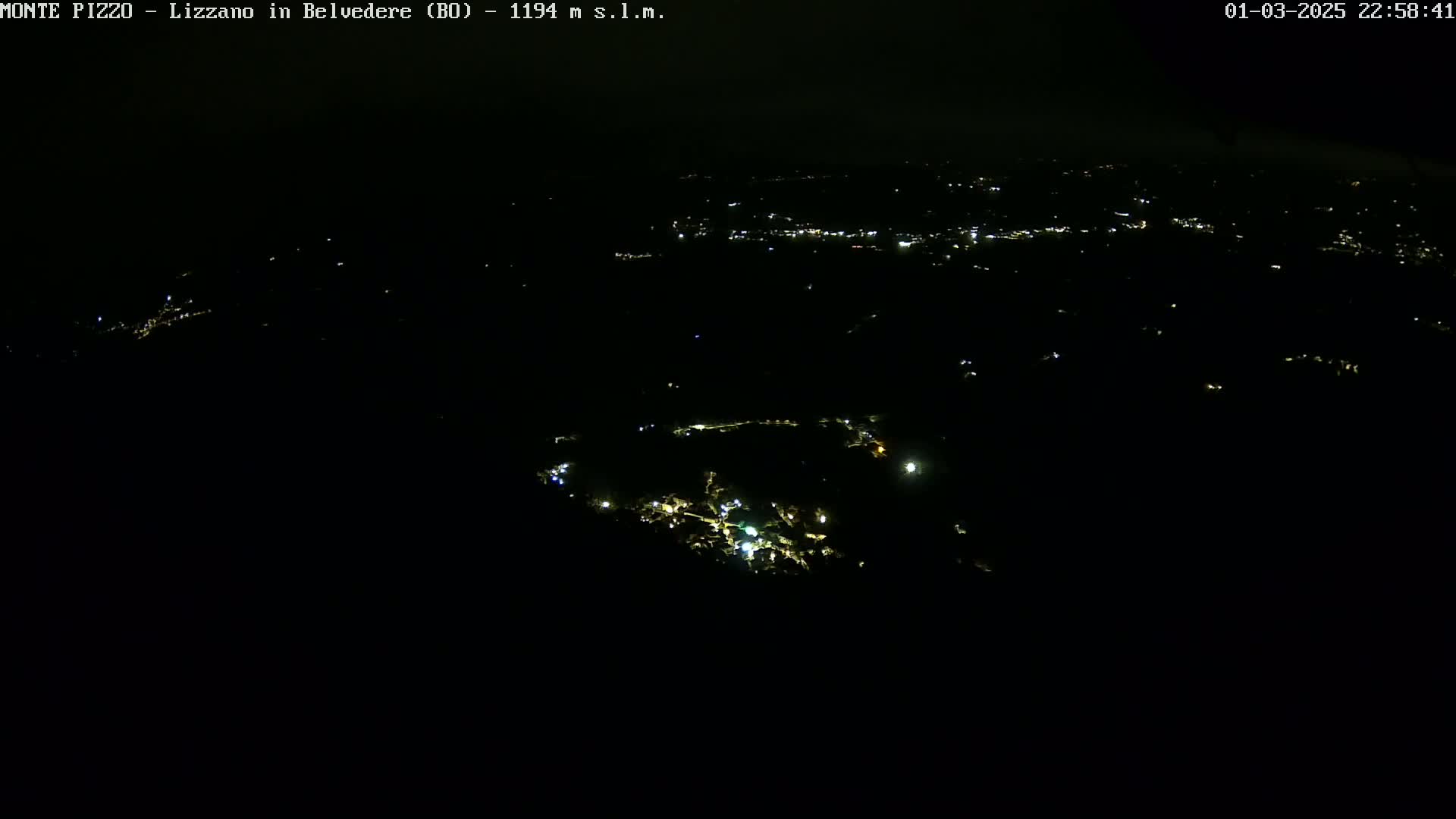 A nighttime aerial view shows a scattering of small, faint lights across a dark landscape.