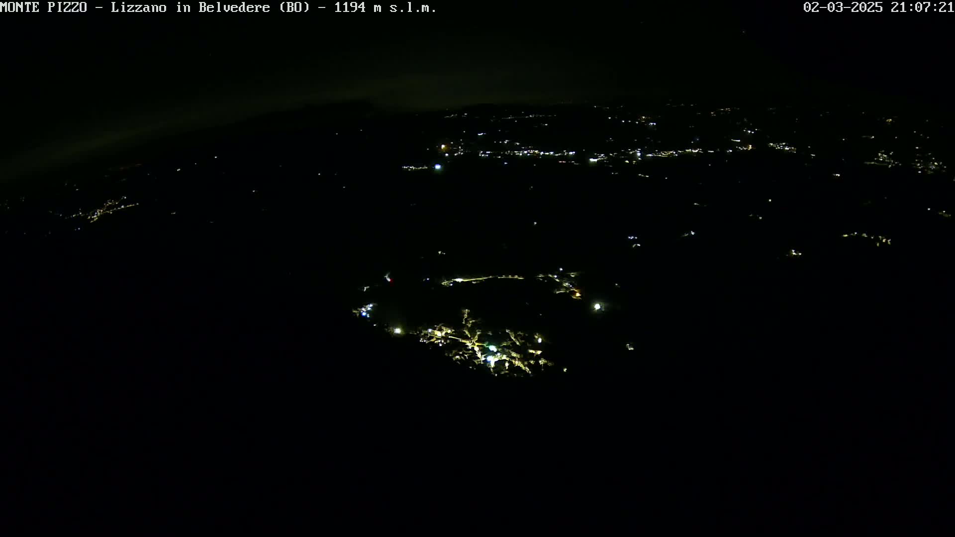 A nighttime aerial view shows a dark landscape speckled with faint, scattered lights.