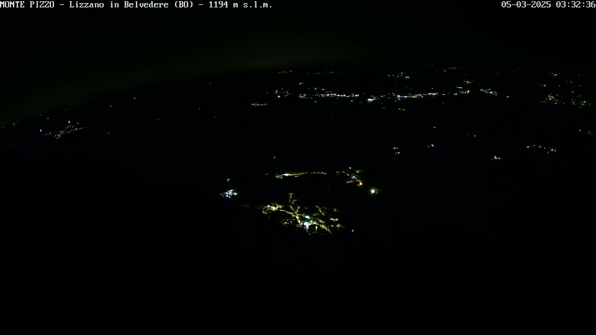A nighttime, high-angle view shows a dark landscape sparsely dotted with small, scattered lights.