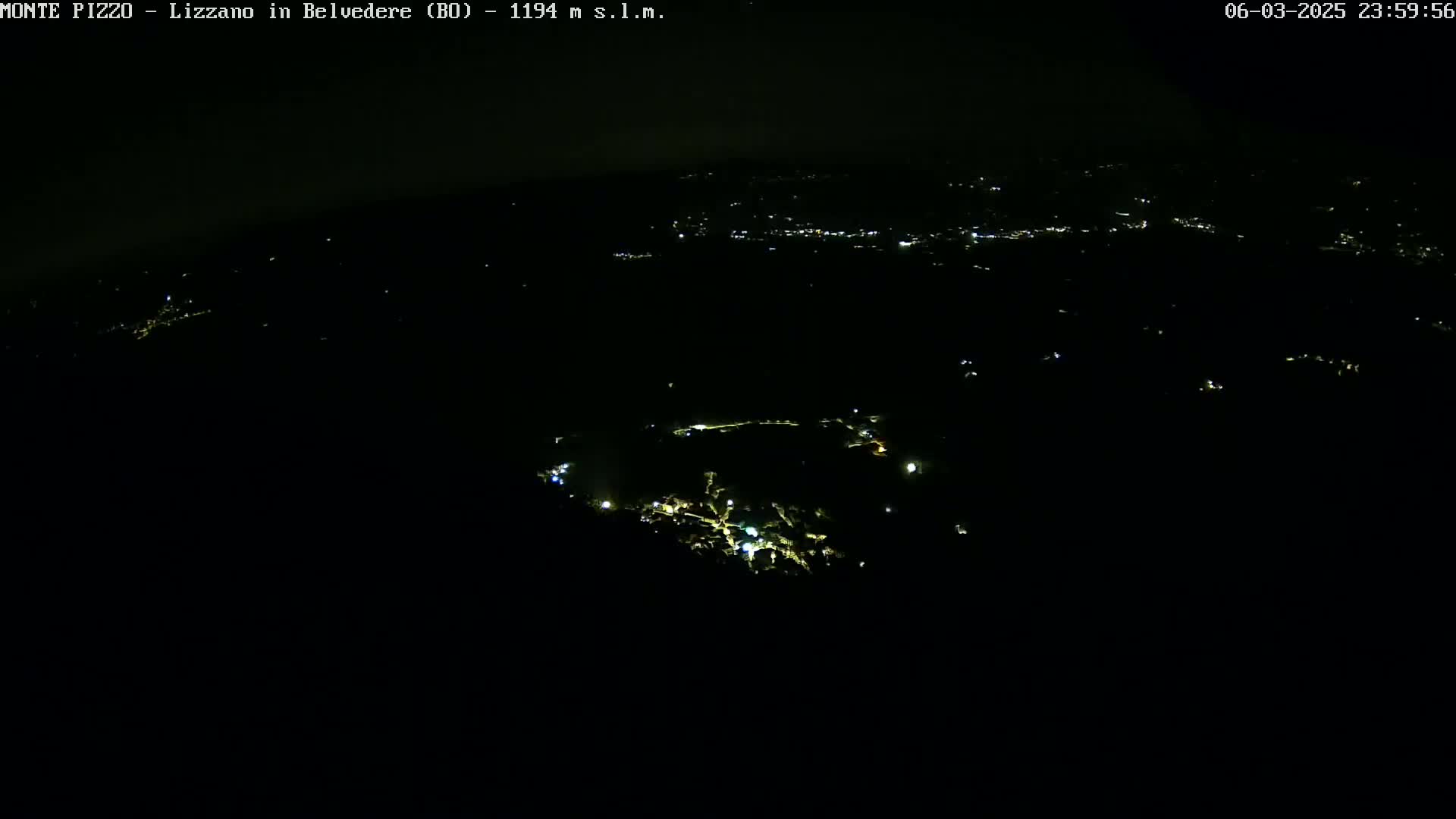 A nighttime, high-angle view shows a small town's scattered lights against a dark landscape.