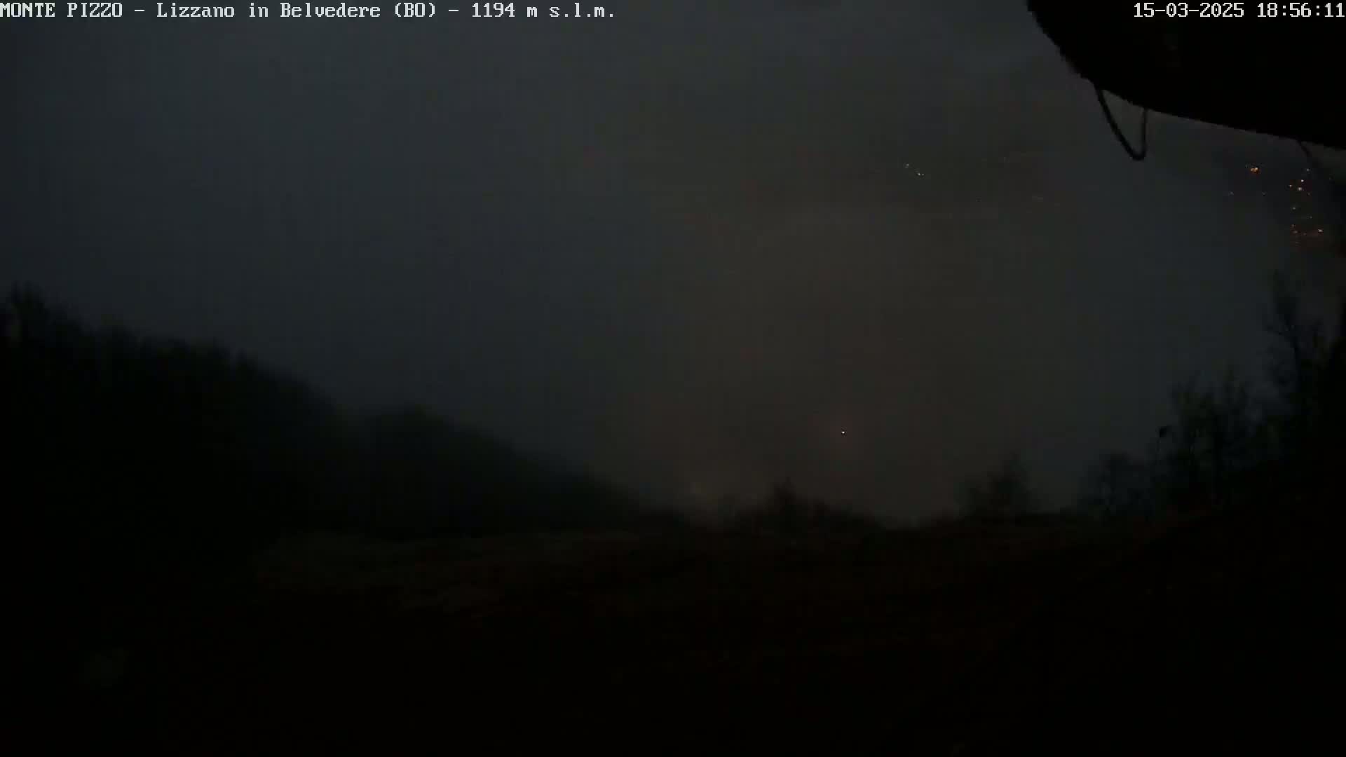 A dark, foggy landscape is visible at night, with a few faint lights in the distance.