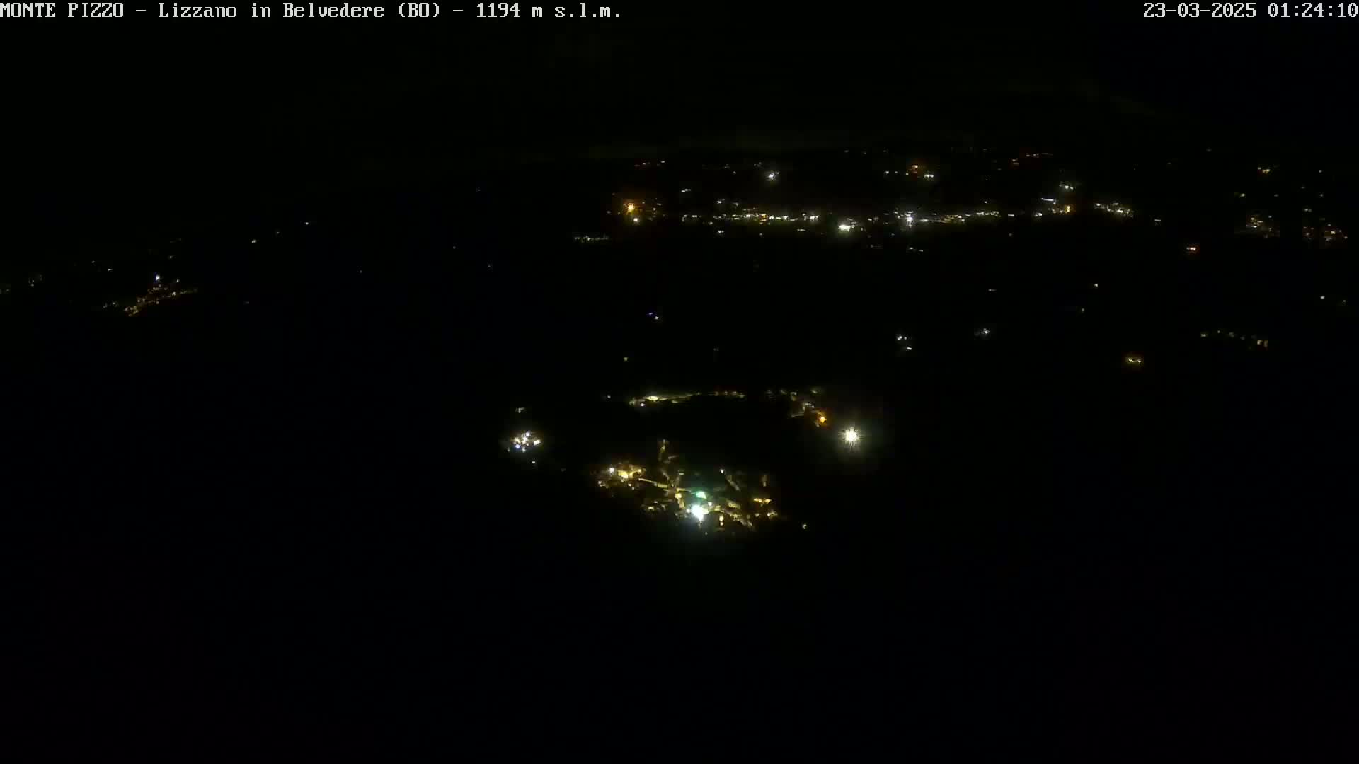 A nighttime aerial view shows a small town with scattered lights under a dark sky.