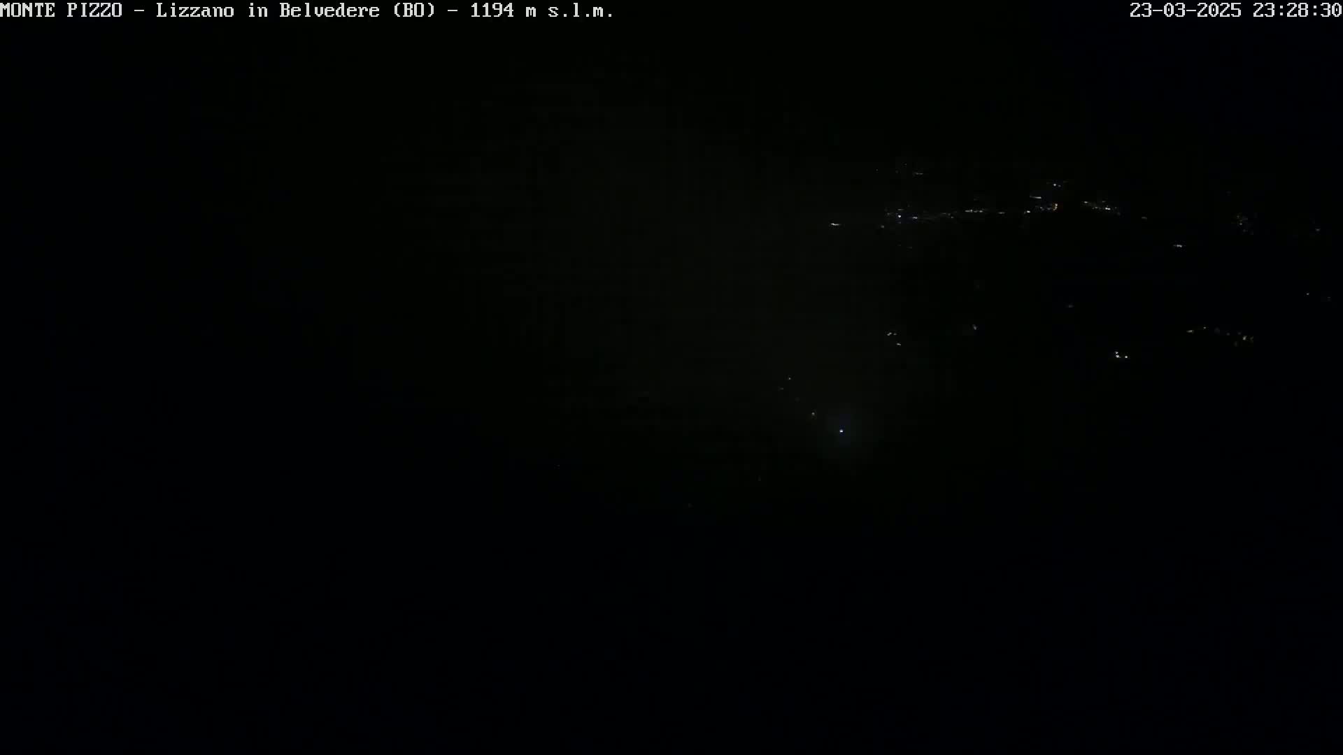 A dark, nighttime view of a distant, sparsely lit landscape.