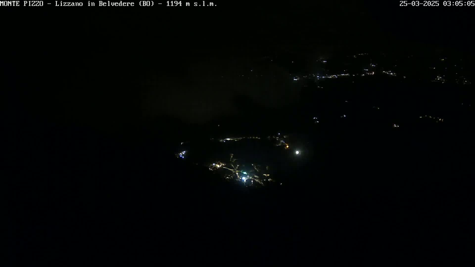 A nighttime aerial view shows a small town illuminated by scattered lights under a dark sky.