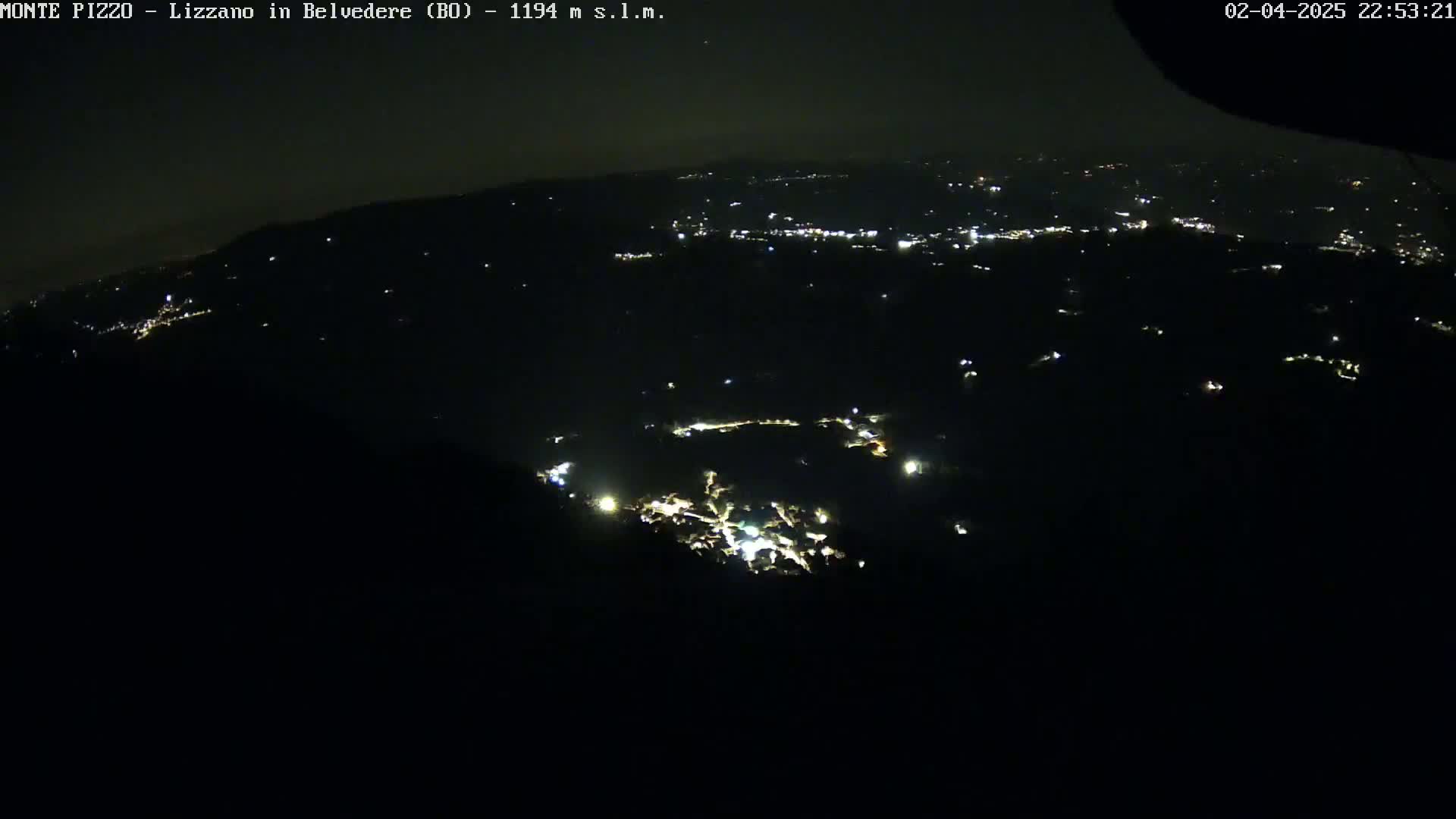 A nighttime, high-angle view shows a dark landscape speckled with small, scattered lights.