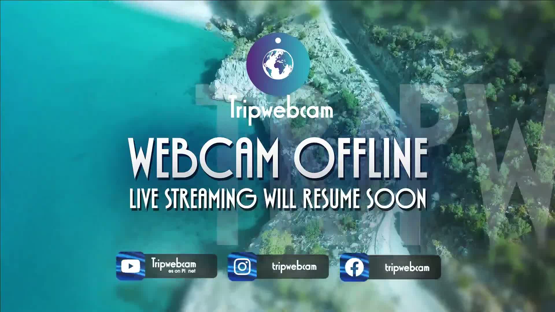 An aerial view of a coastline with turquoise water and green vegetation shows a webcam offline message.