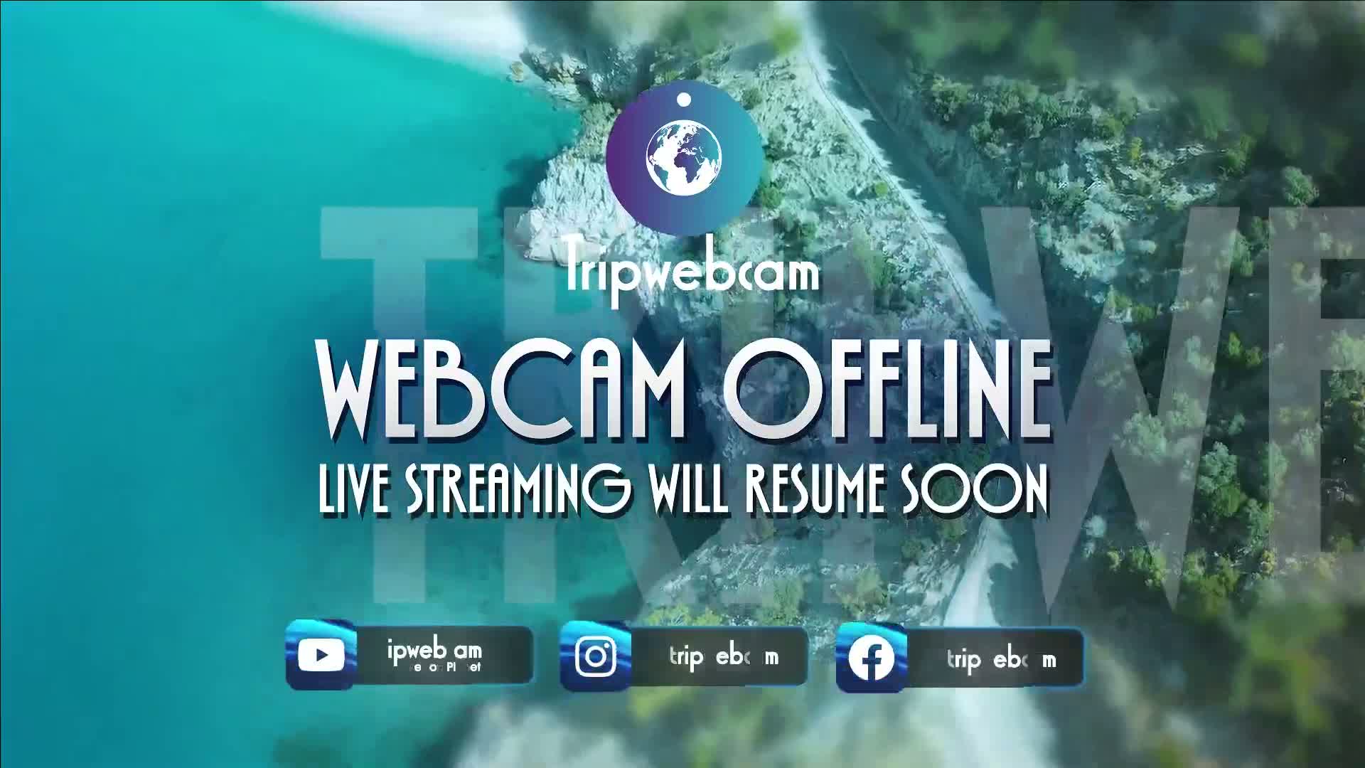 An aerial view of a rocky coastline meeting turquoise water shows a webcam offline message.