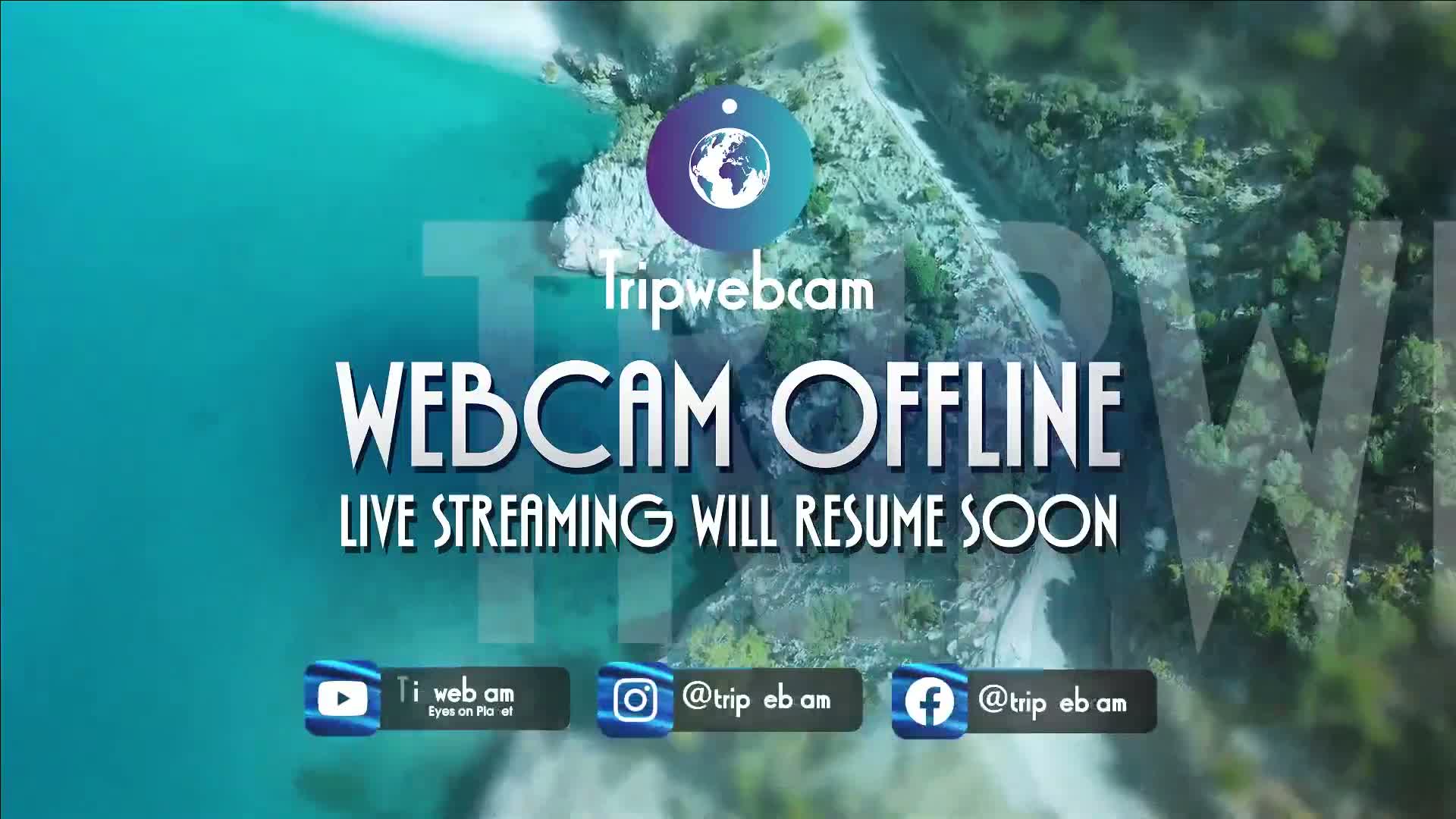 An aerial view of a rocky coastline meeting turquoise water shows a webcam offline message.