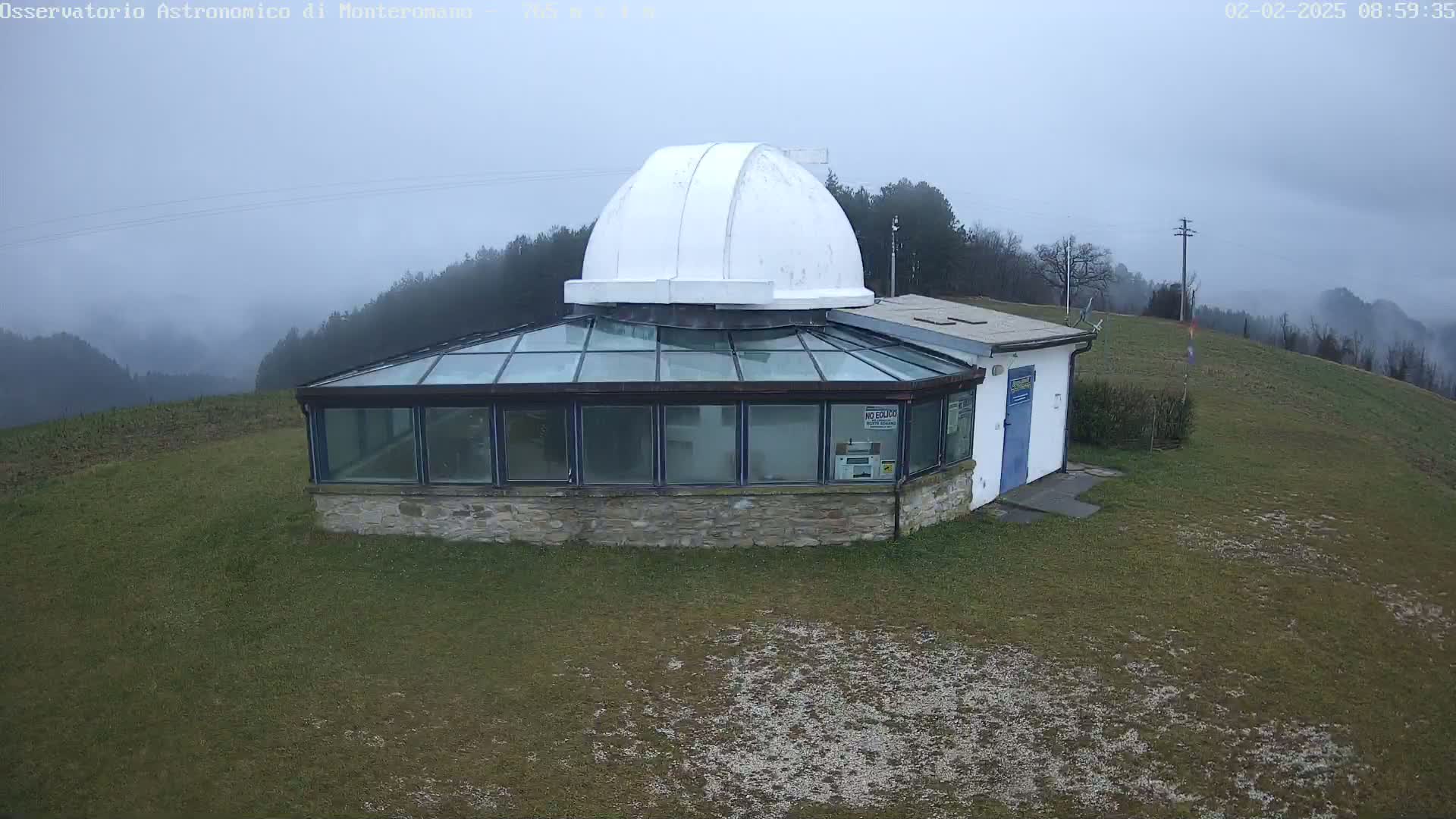 A stone building with a glass-roofed addition and a white dome sits on a grassy hilltop in foggy conditions.