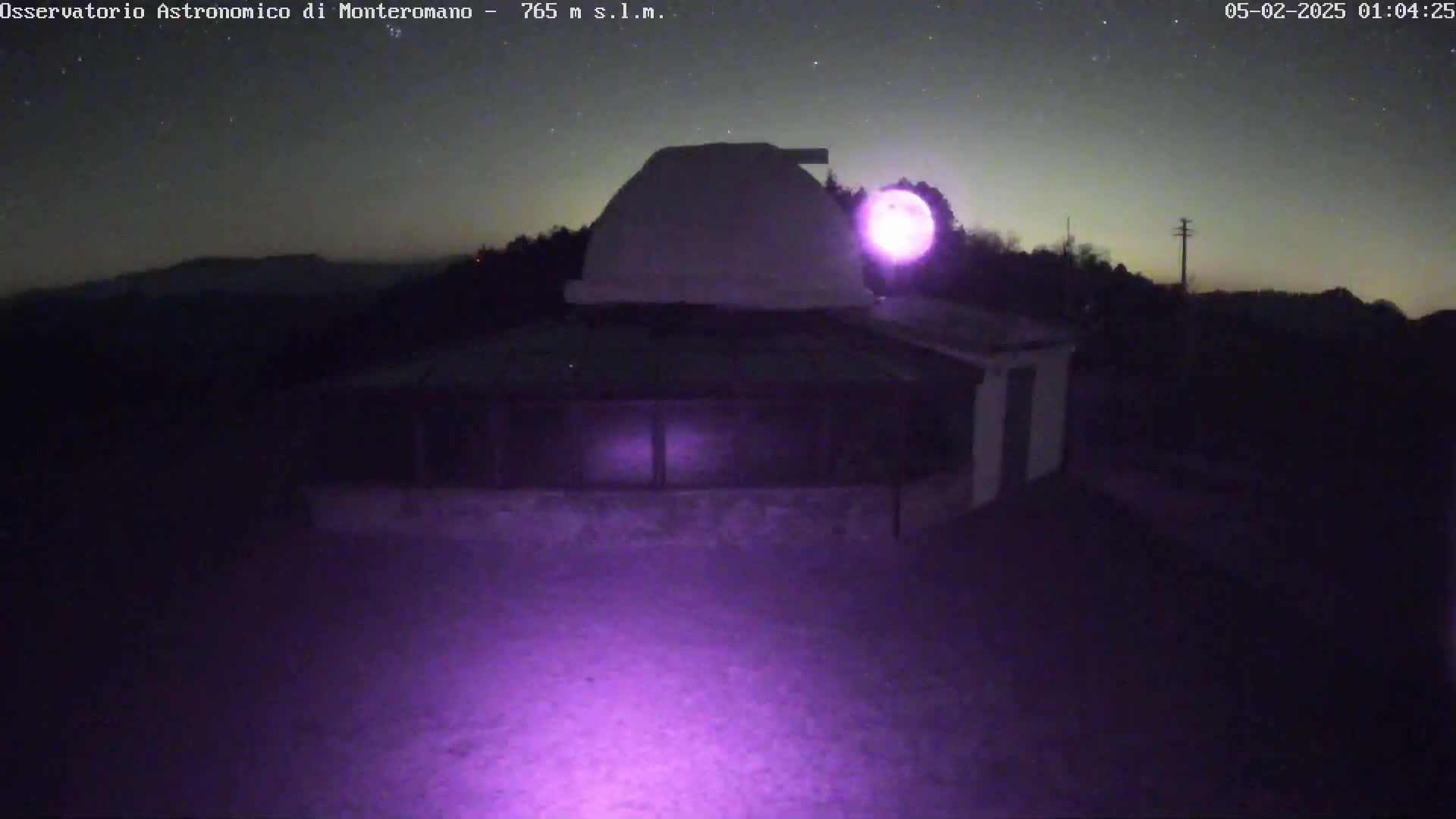 A nighttime image shows a building with a dome-shaped roof under a starry sky.