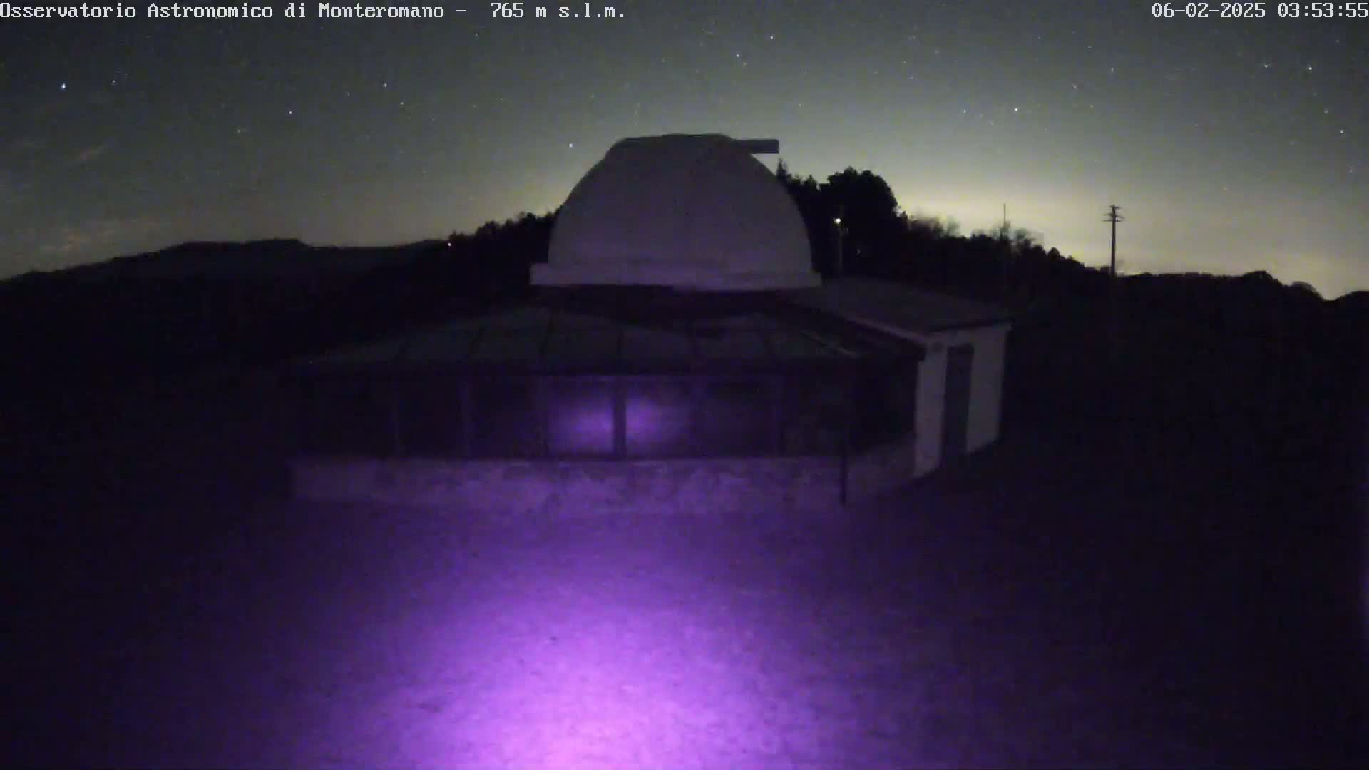 A nighttime view of an observatory with a dome, under a clear, starry sky.