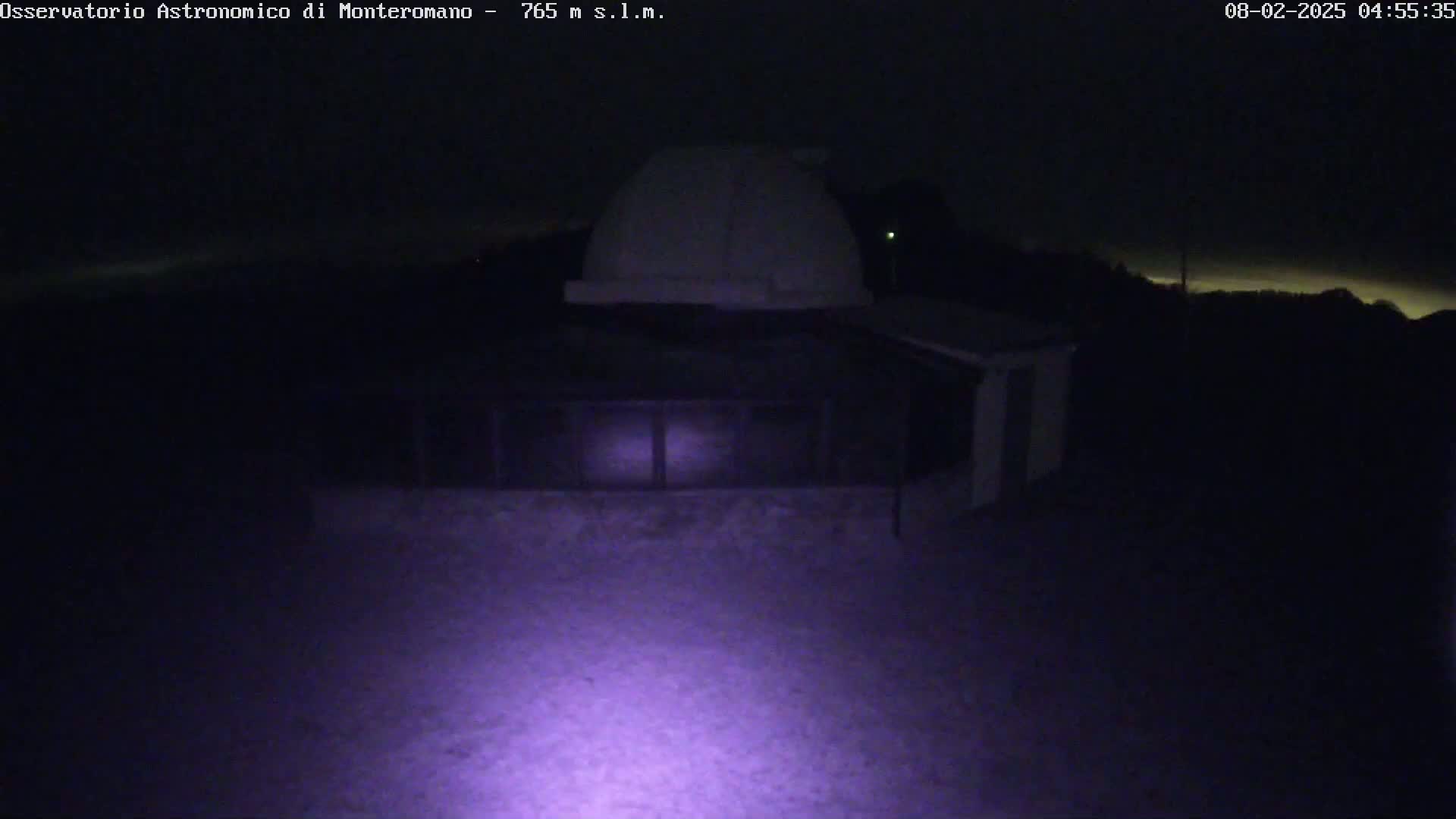 A nighttime view of an observatory building with a dome under a dark sky.