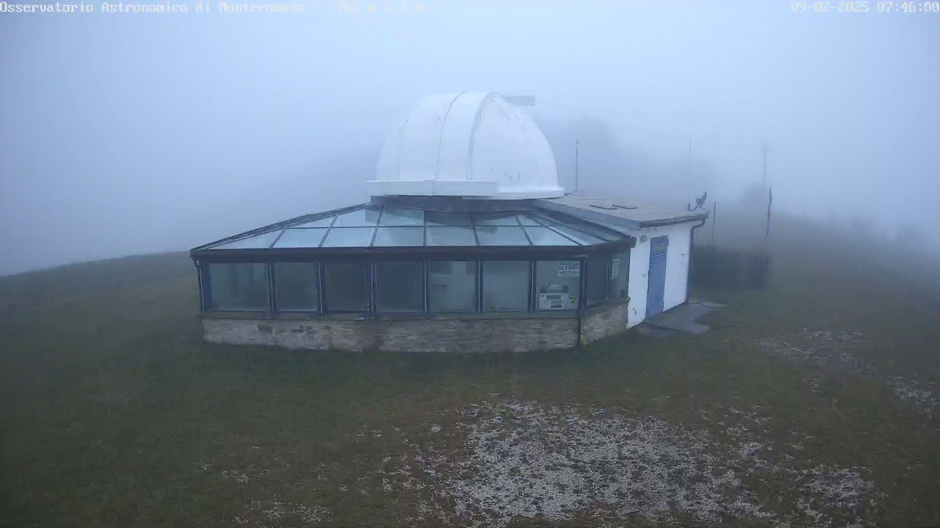 A white-domed observatory building with a glass-roofed addition sits in a foggy field.