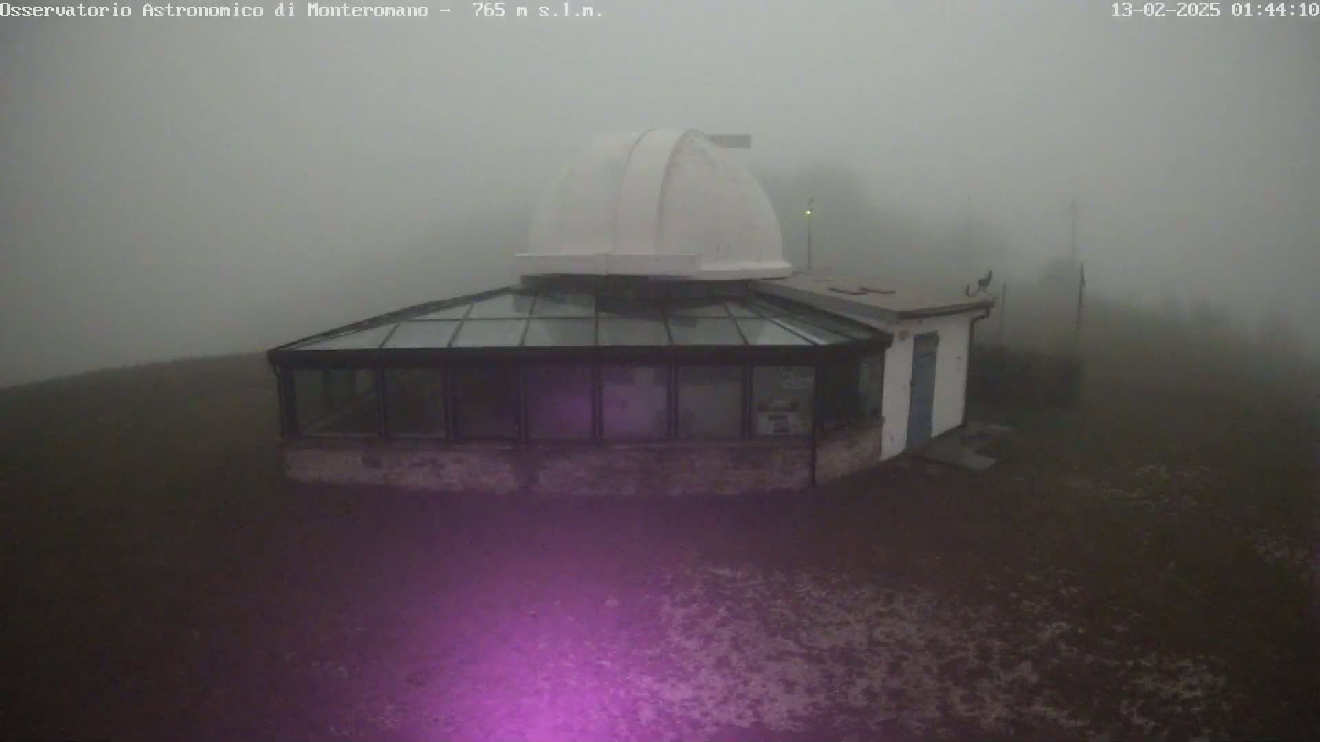 A white-domed observatory building with a glass-roofed addition is shrouded in thick fog.