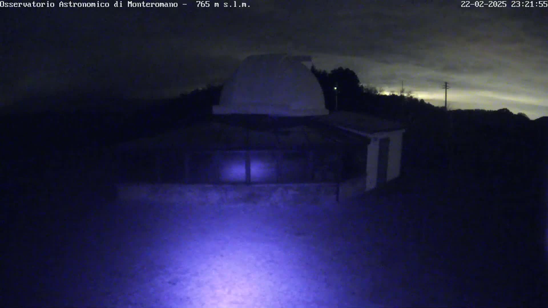 A nighttime view of an observatory with a dome under a cloudy sky.